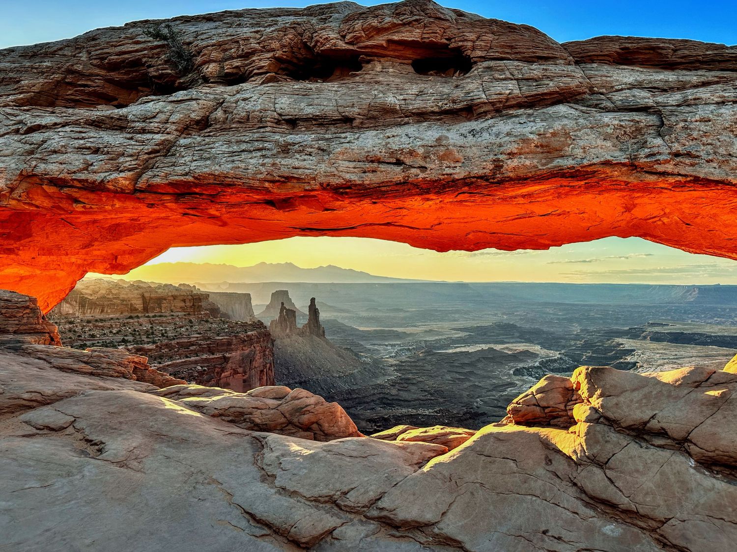 Mesa Arch in Canyonlands National Park glowing orange during sunrise.