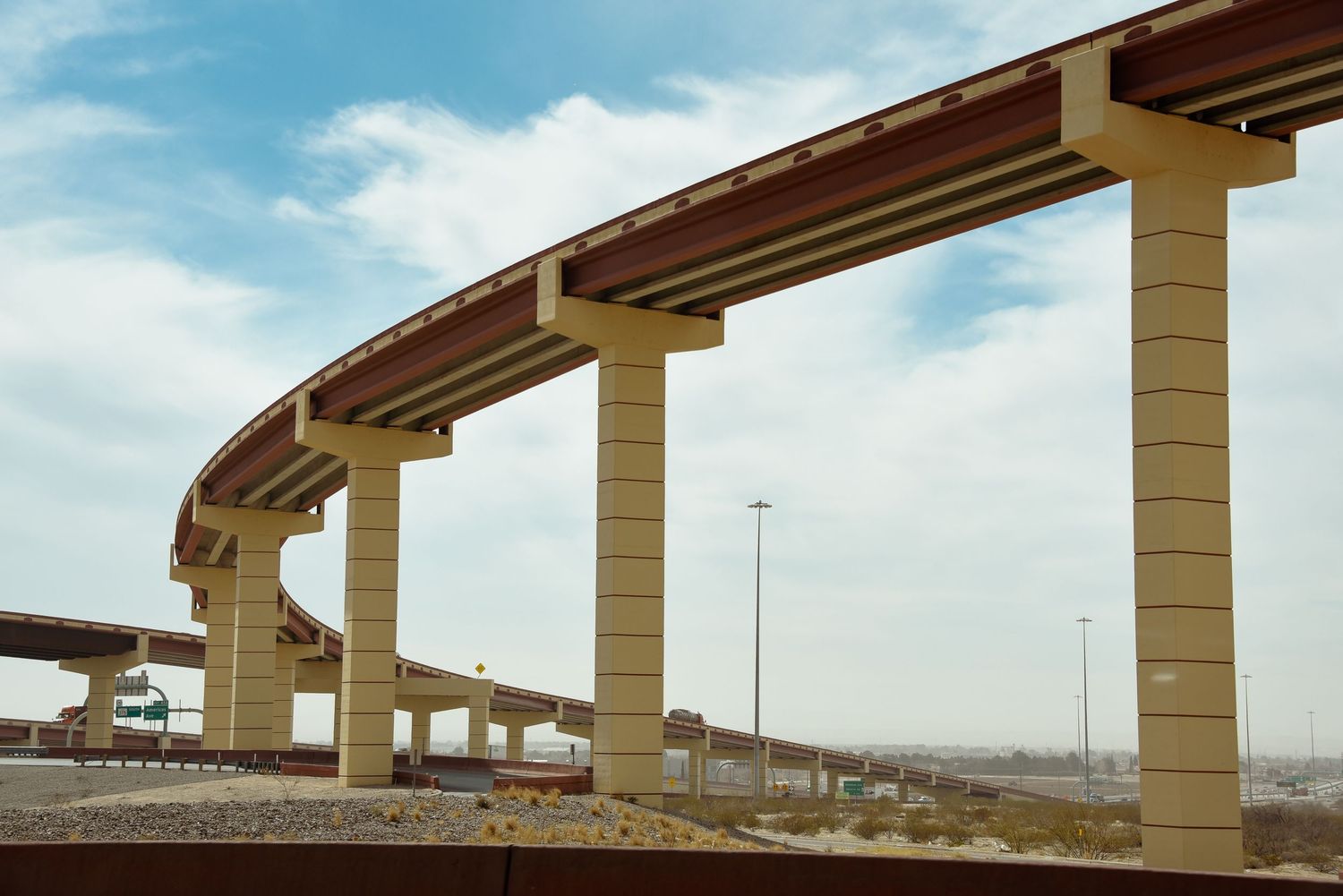 Series of concrete highway overpass pillars stretching across a desert landscape under blue skies.
