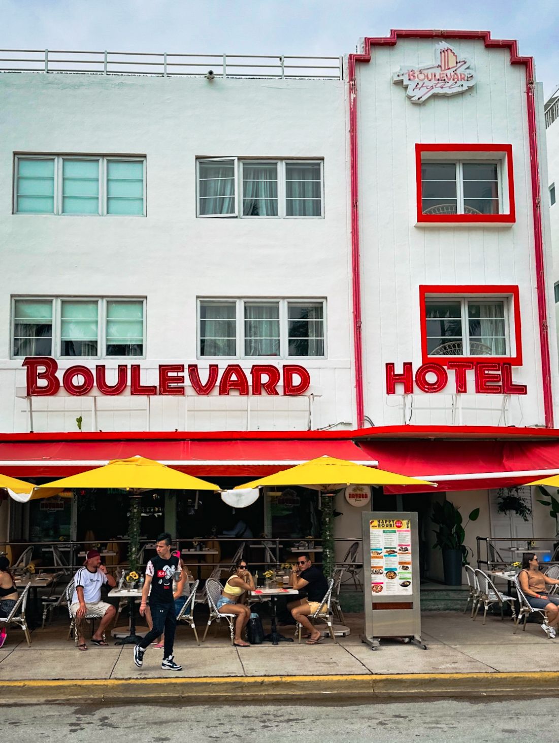 Art deco style Boulevard Hotel with white facade and red trim in urban setting.