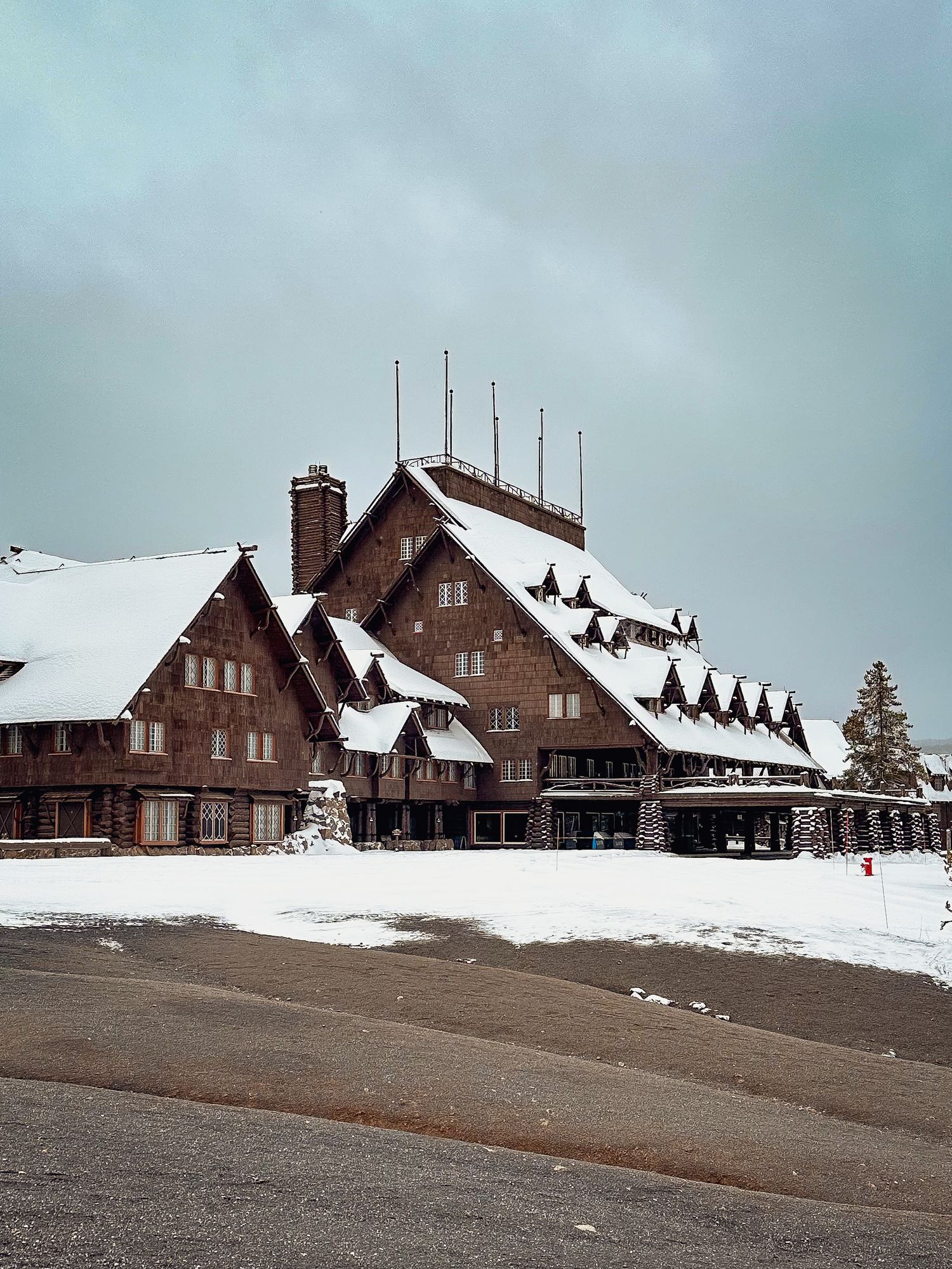 Historic snow-covered lodge buildings with multiple chimneys set against a cloudy winter sky.