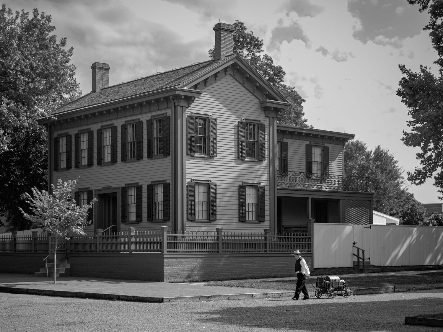 Historic white colonial buildings with black shutters in black and white photograph.