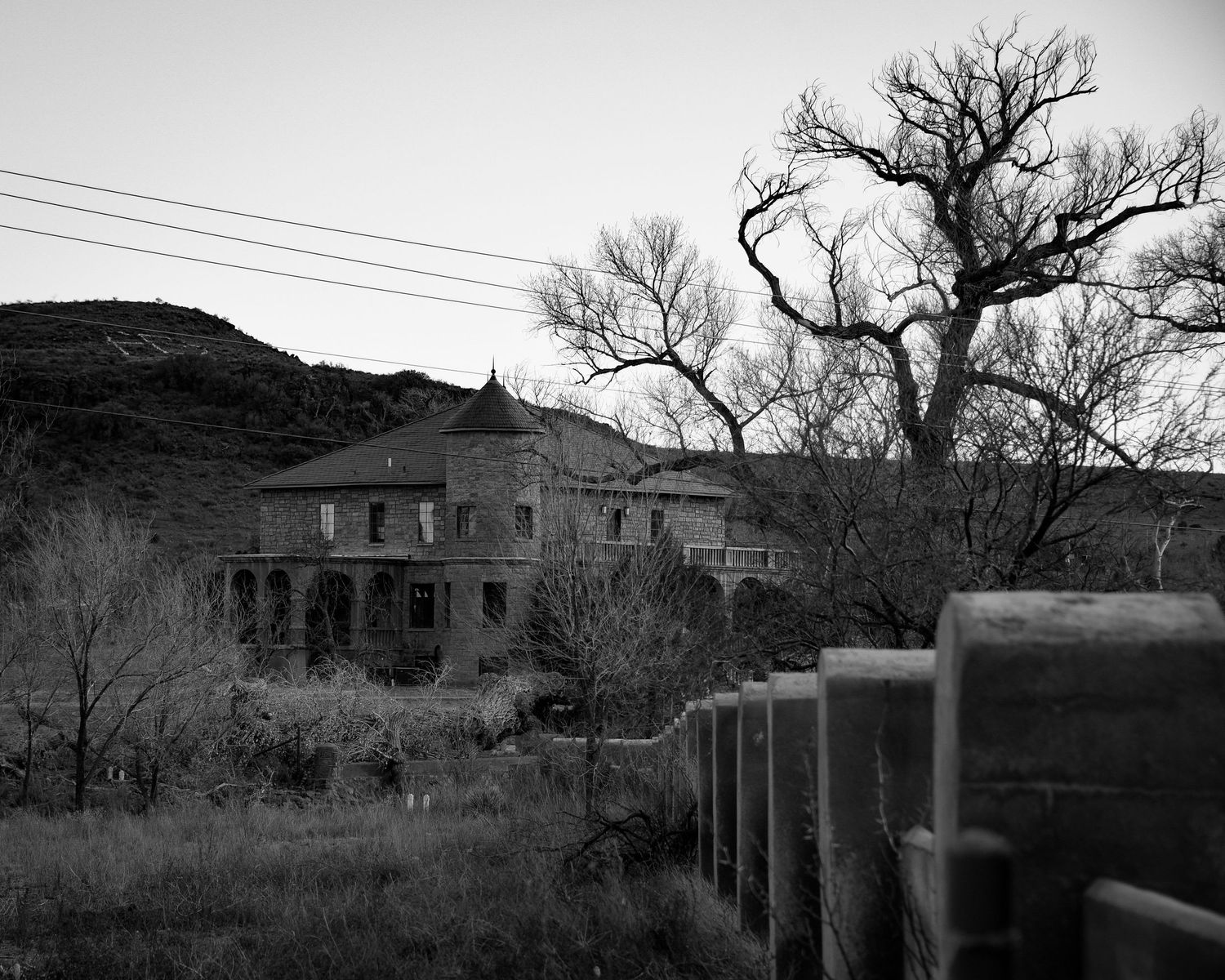 Abandoned buildings and bare trees create a haunting black and white landscape.