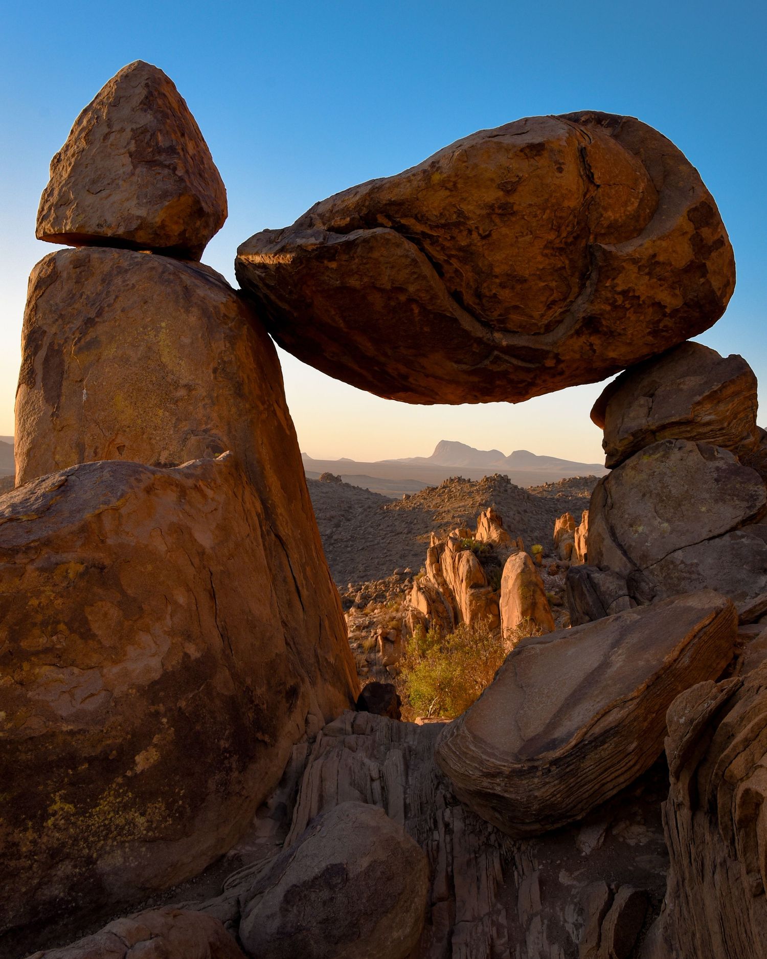 Dramatic rock formations and arches in a desert landscape at sunset.