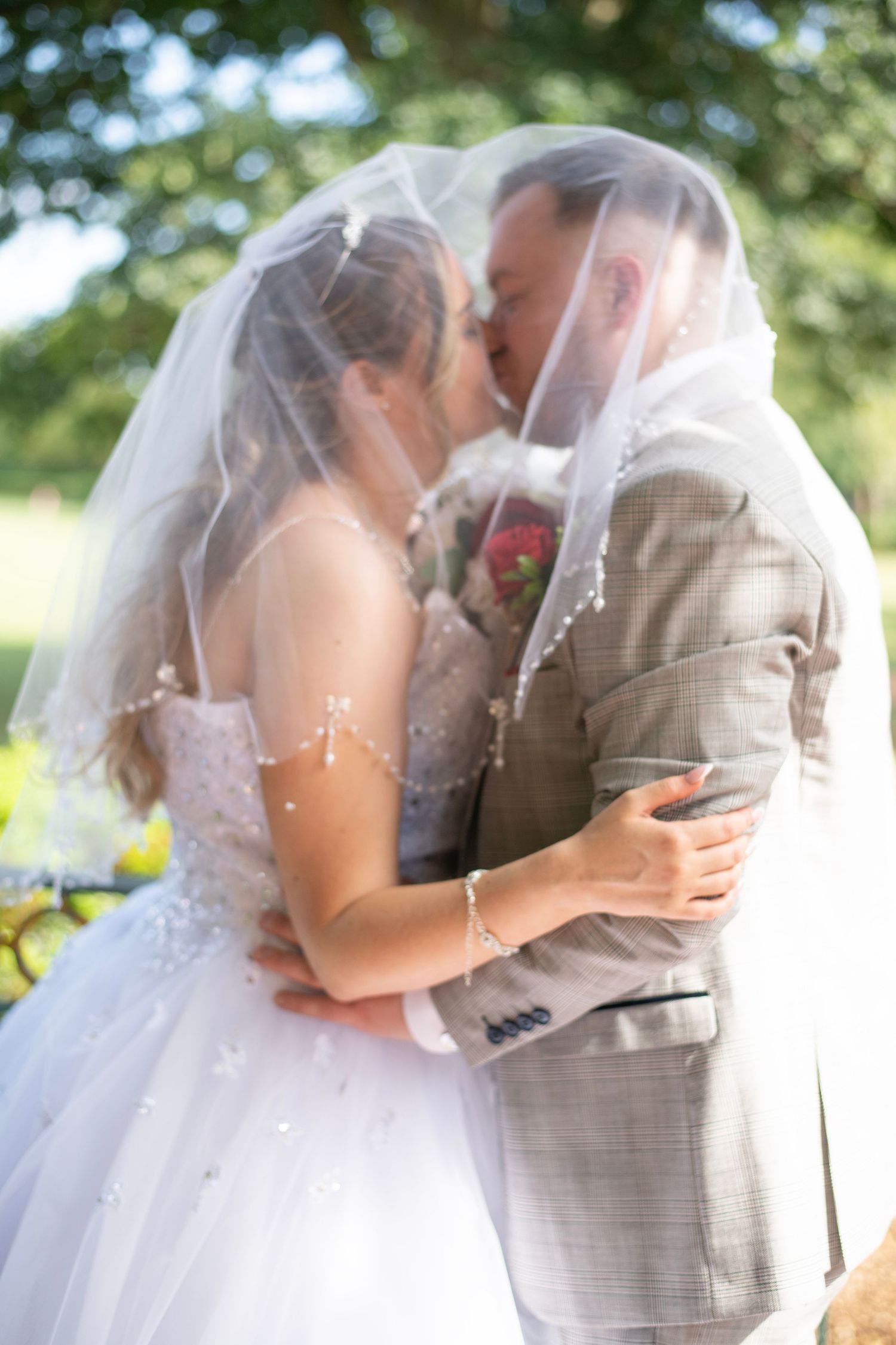 Four romantic wedding photos show a couple kissing with the bride in a white dress and veil and groom in plaid suit.