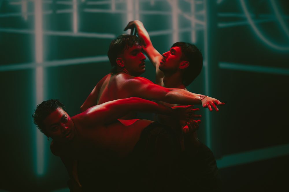 Dancers in red lighting creating dramatic poses during performance.