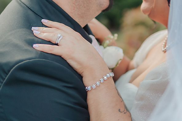 Closeup picture of hands touching during an intimate wedding moment with elegant rings and formal attire.