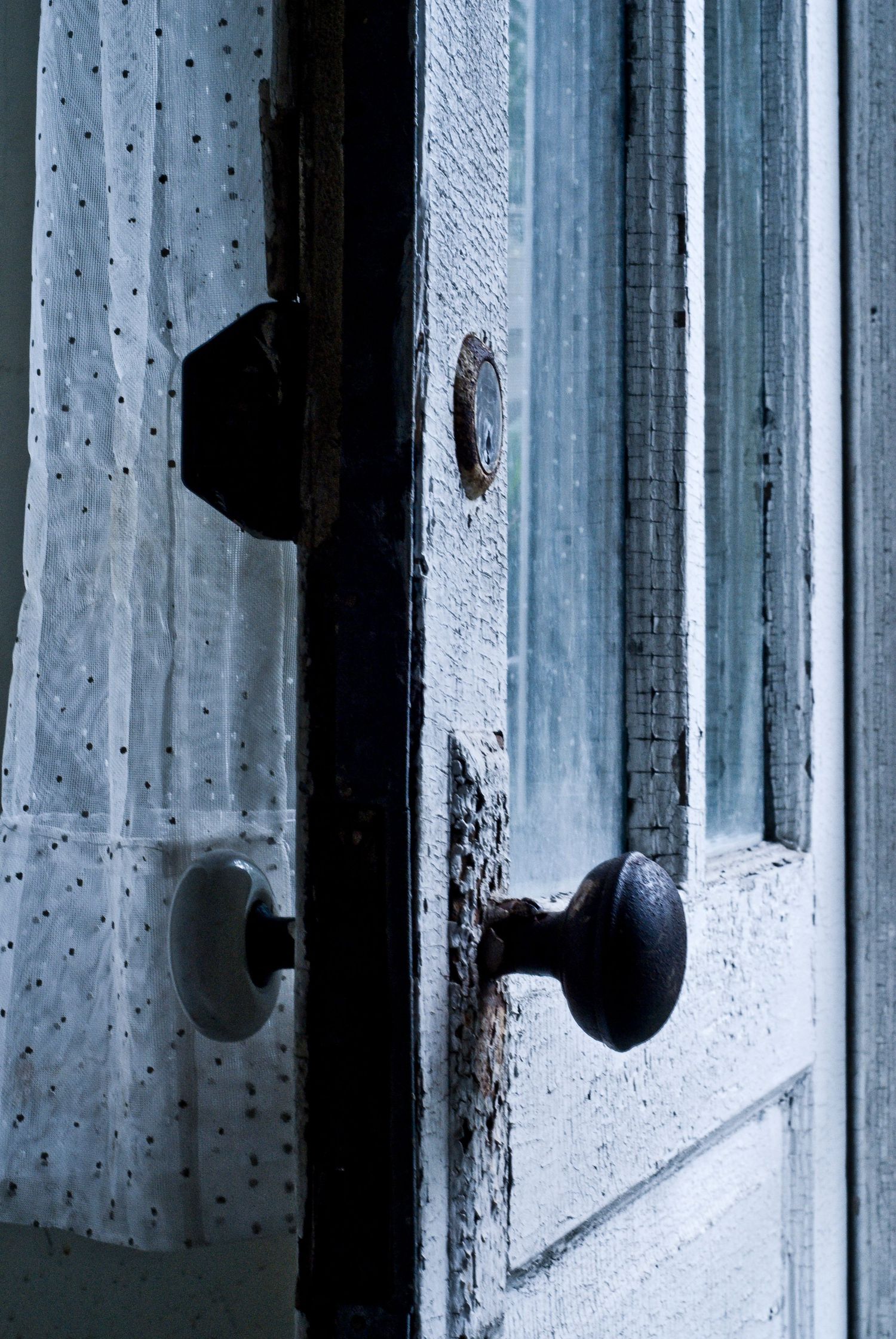 Vintage door knobs and lace curtain in soft moody lighting.