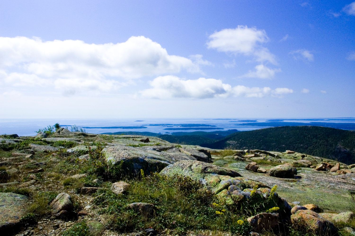 Top of Cadillac Mountain Acadia National Park in Maine view summit overlooking a vast coastal landscape with blue water and distant islands.