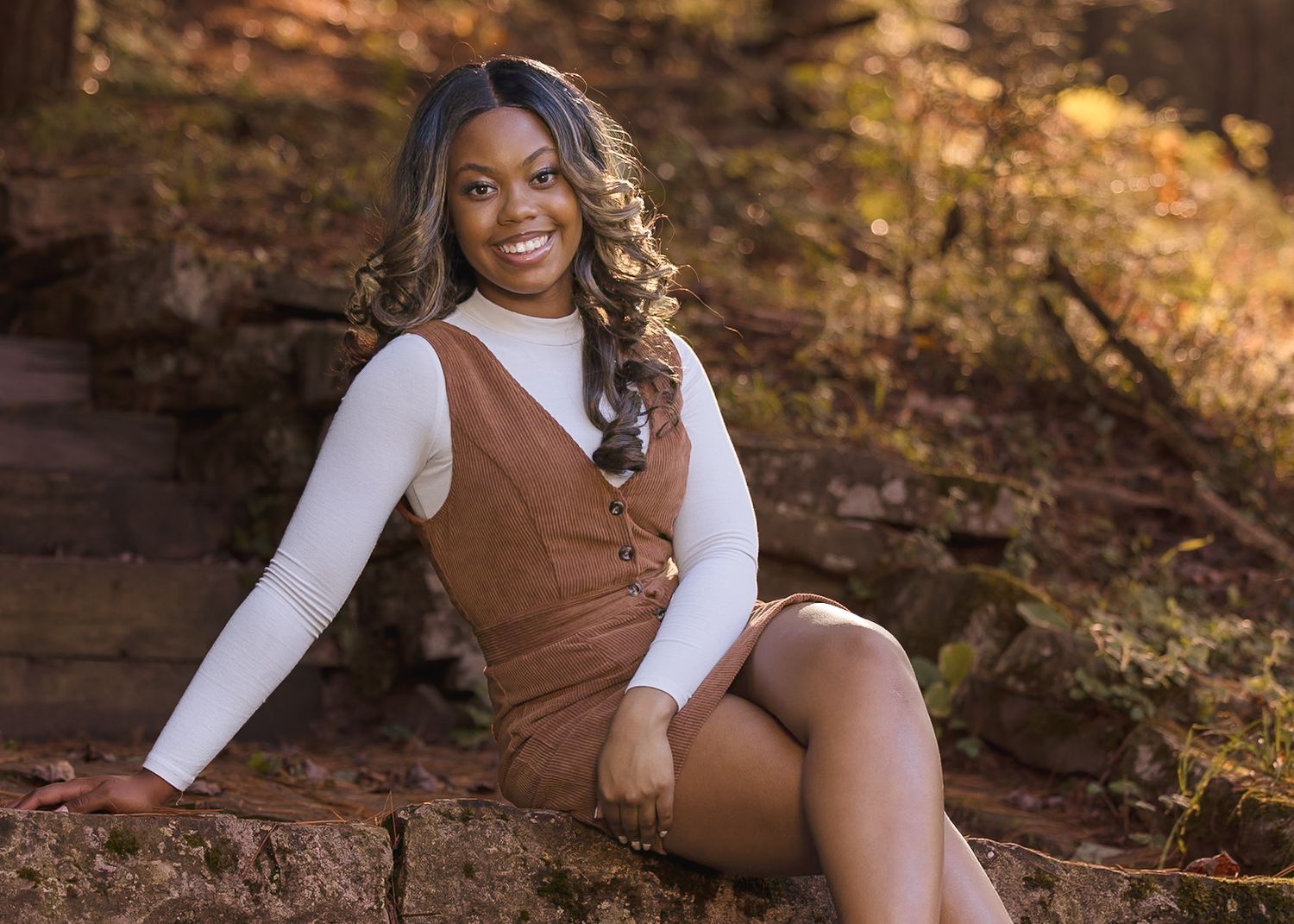 Autumn outdoor portrait session with warm golden lighting and natural rock formations.
