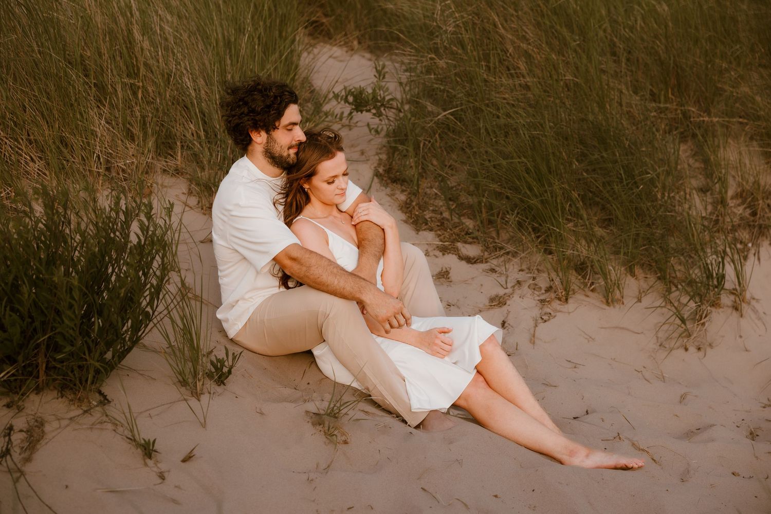 Dreamy beachside photography sequence featuring romantic poses in white attire on sandy dunes at sunset. Rachel Martinez Photography