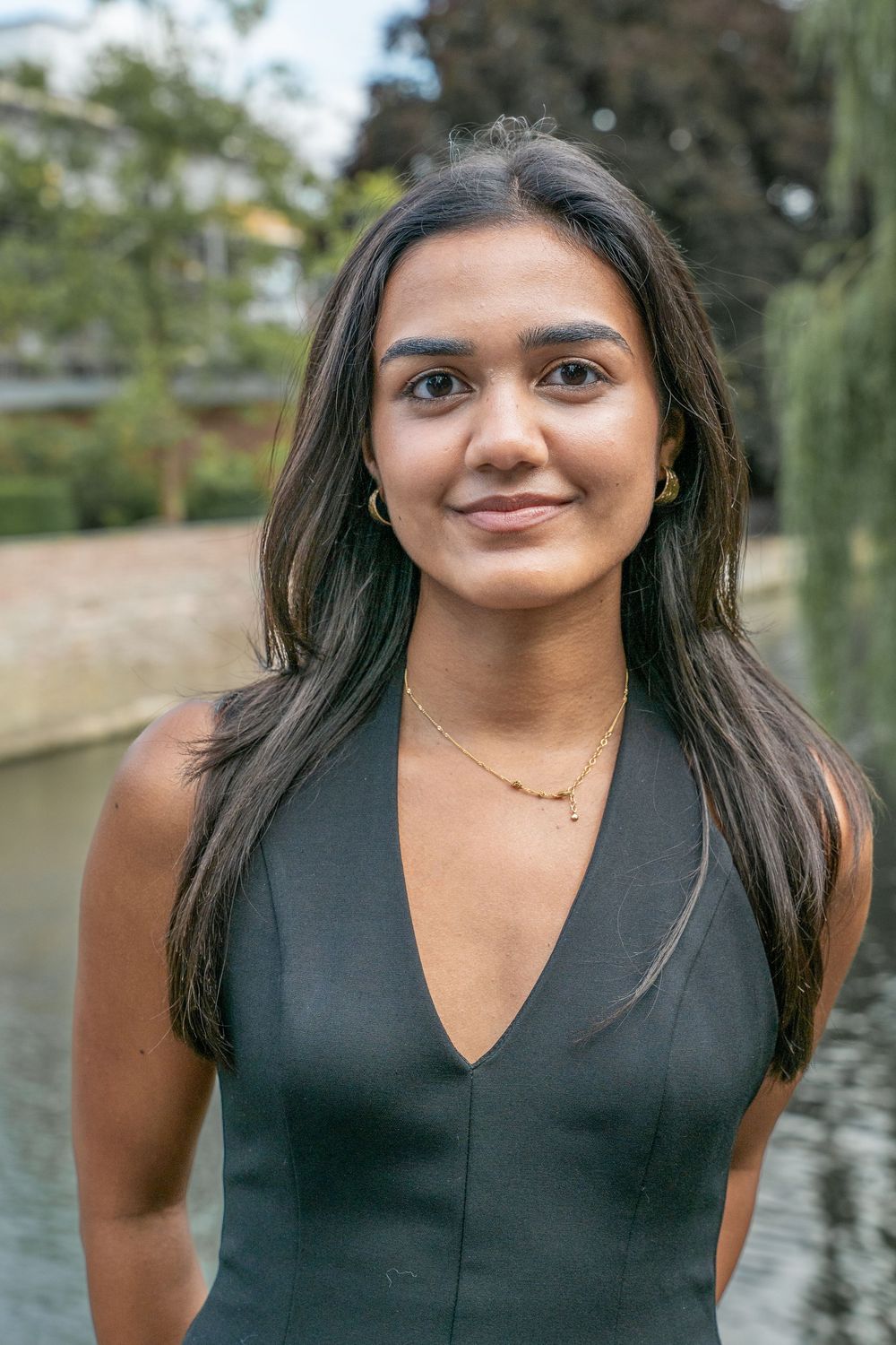 Portrait sequence showing someone in a sleeveless black top smiling against a scenic outdoor background with water and trees.