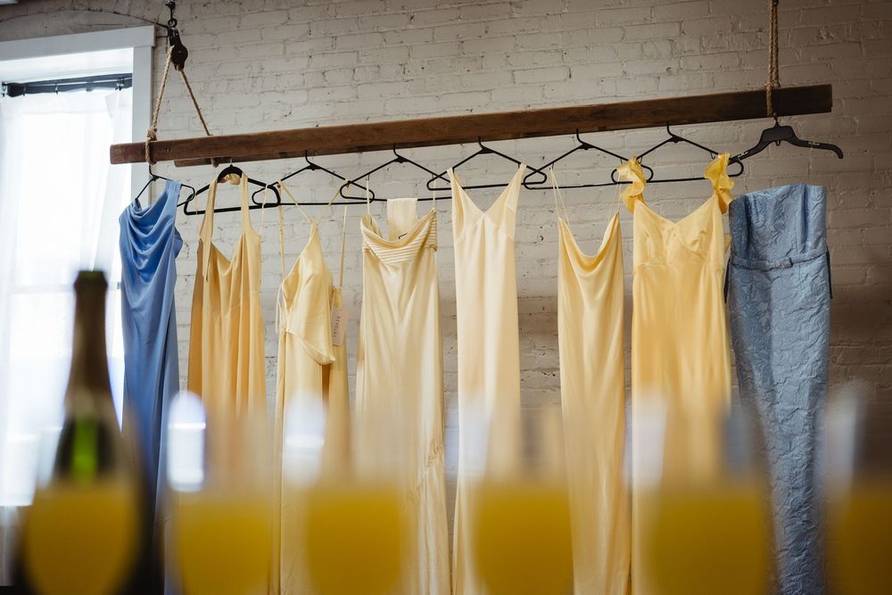 A series of hanging bath towels and clothing on a wire drying rack against a white brick wall.