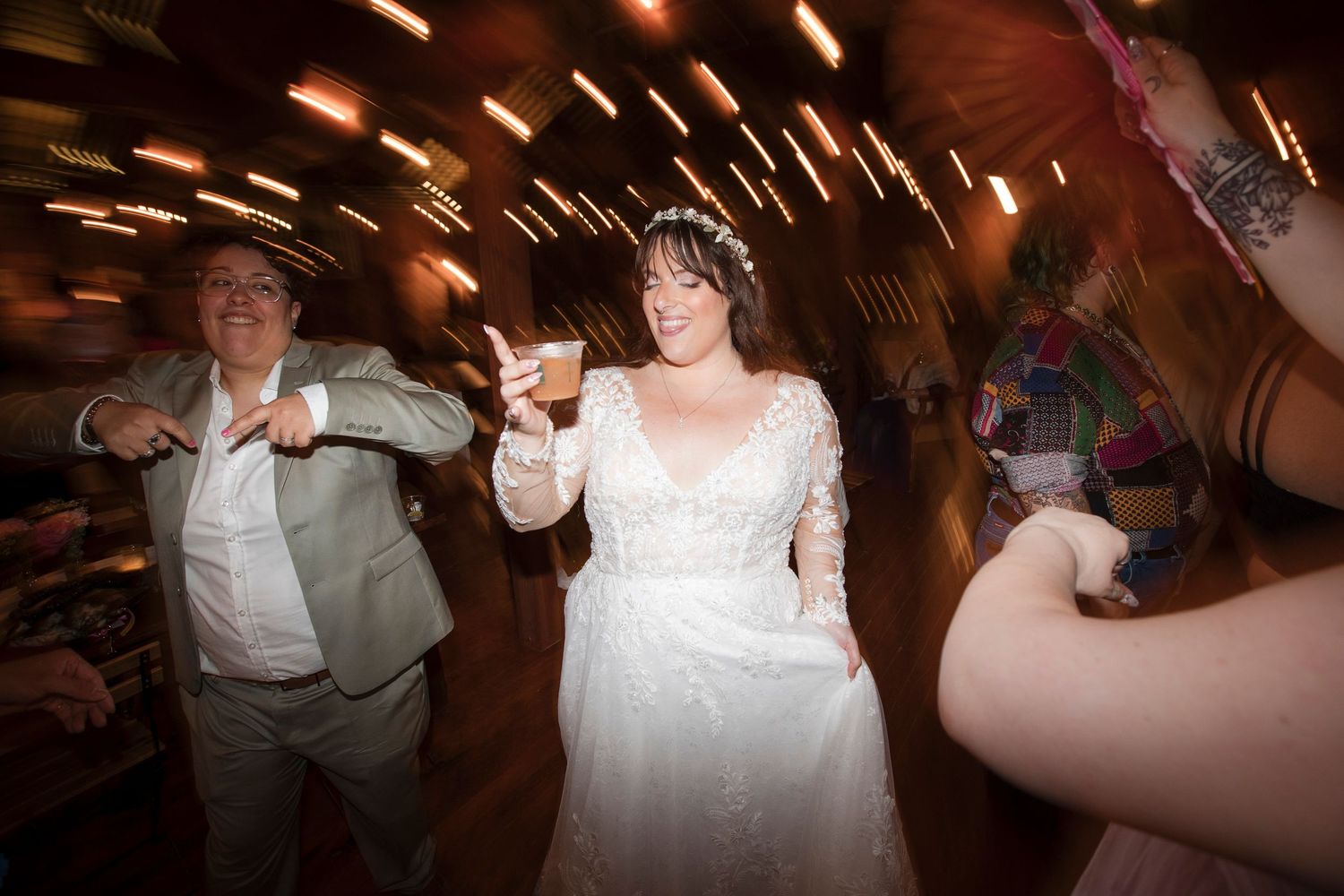 A couple in formal wedding attire spins on the dance floor during their reception celebration.