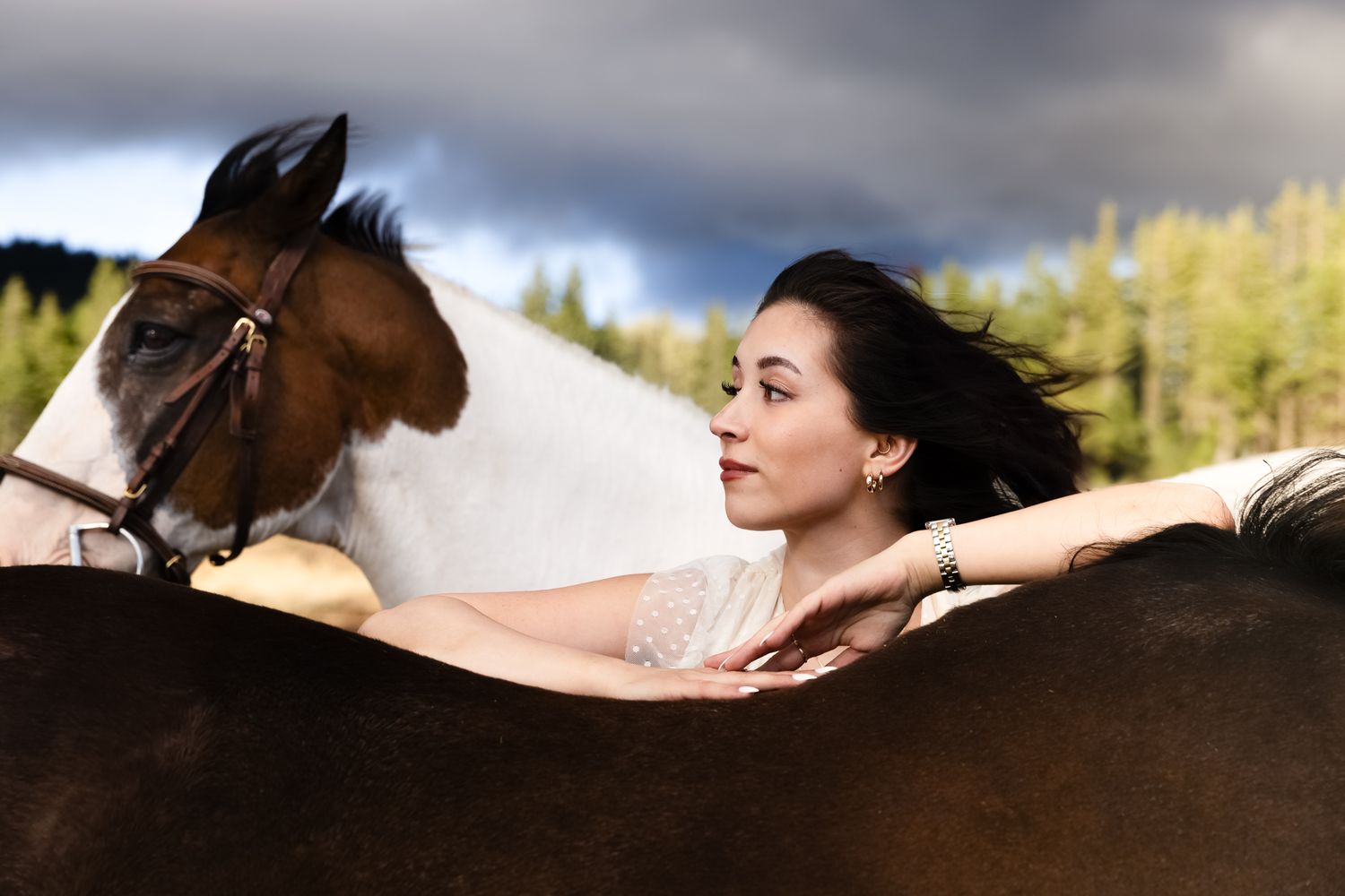 A model with her hair blowing in the wind poses between two horses near Seattle, Washington.
