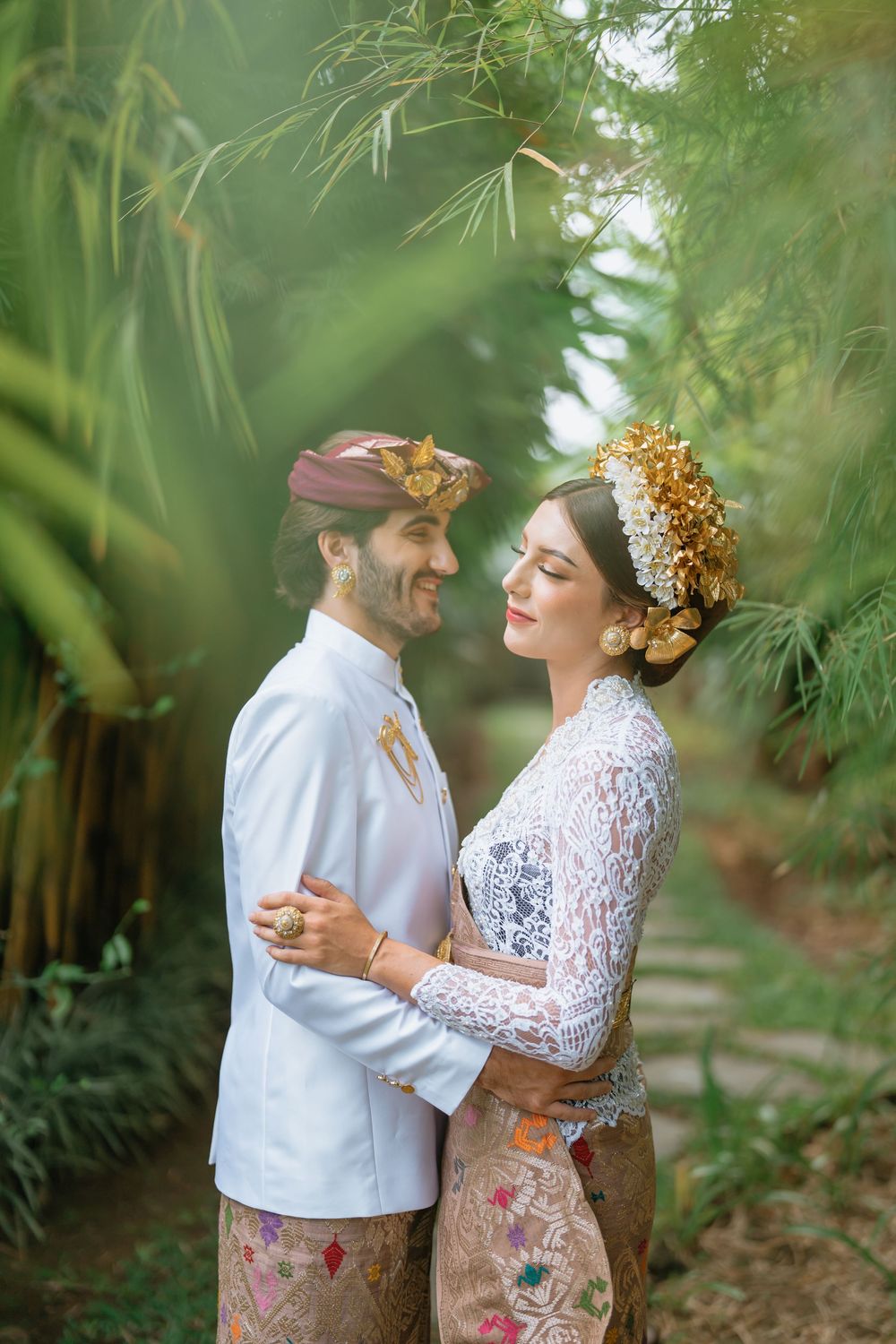 Intimate wedding portrait session in a lush tropical garden with traditional Indonesian clothing.