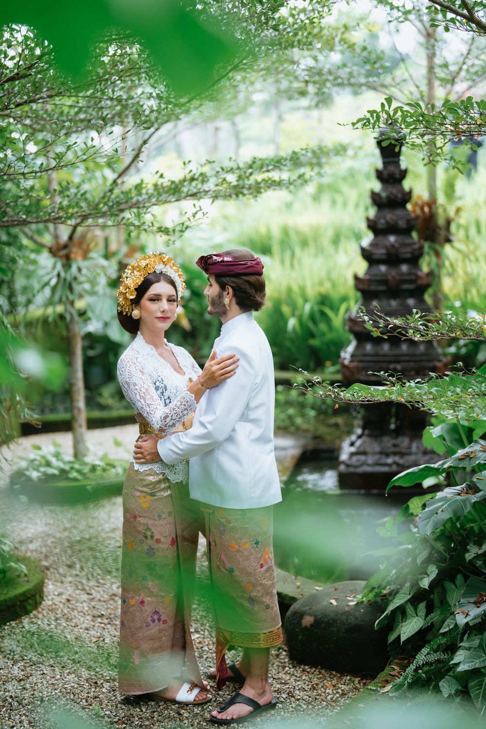 Romantic portrait session in a lush garden with traditional Balinese stone sculptures.