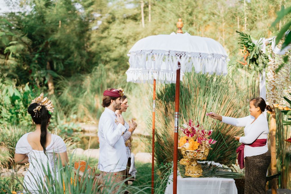 Wedding ceremony in a tropical garden setting with traditional attire and decorations.