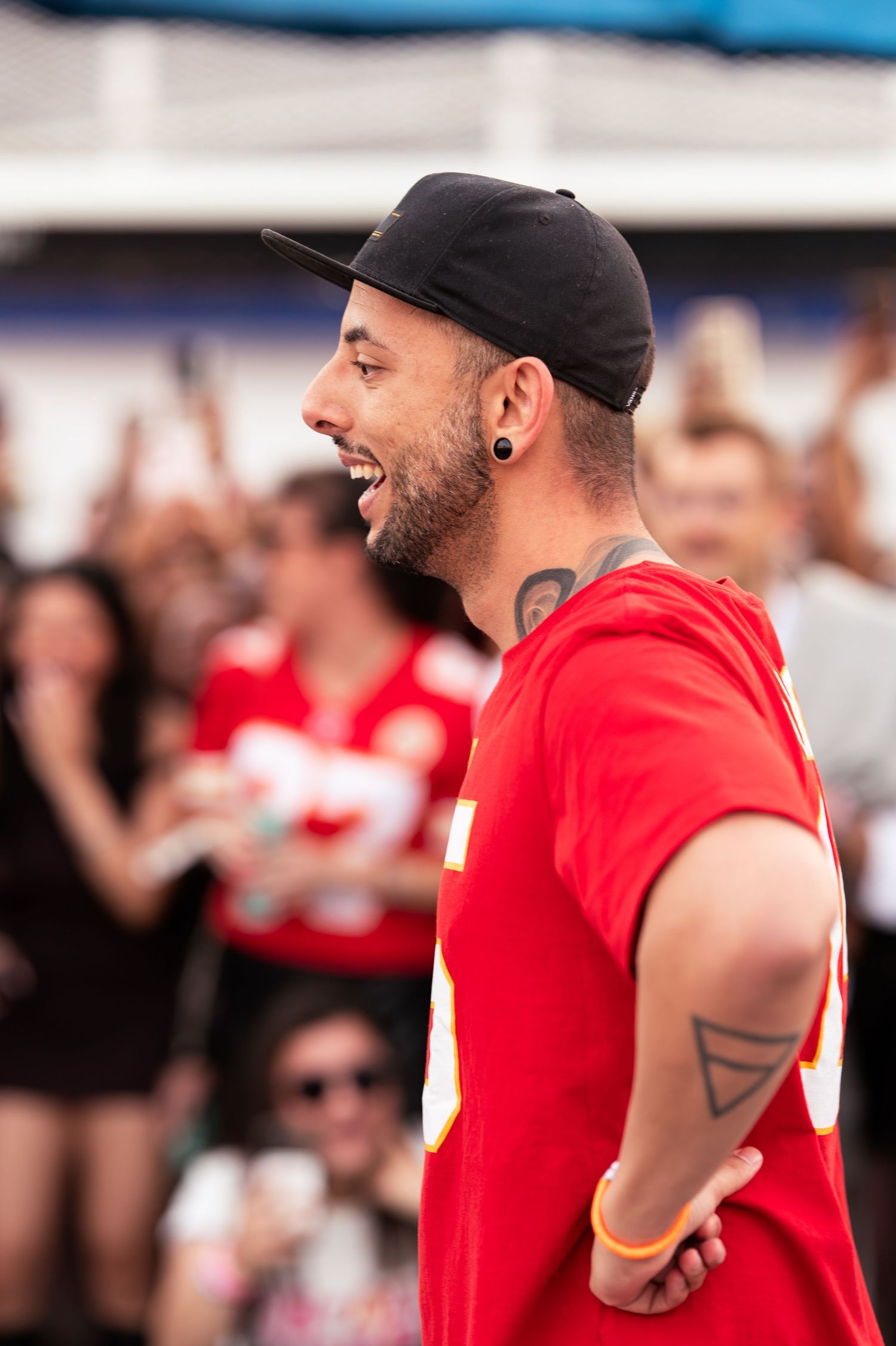 Fan wearing red sports jersey celebrating with animated expressions at stadium event.