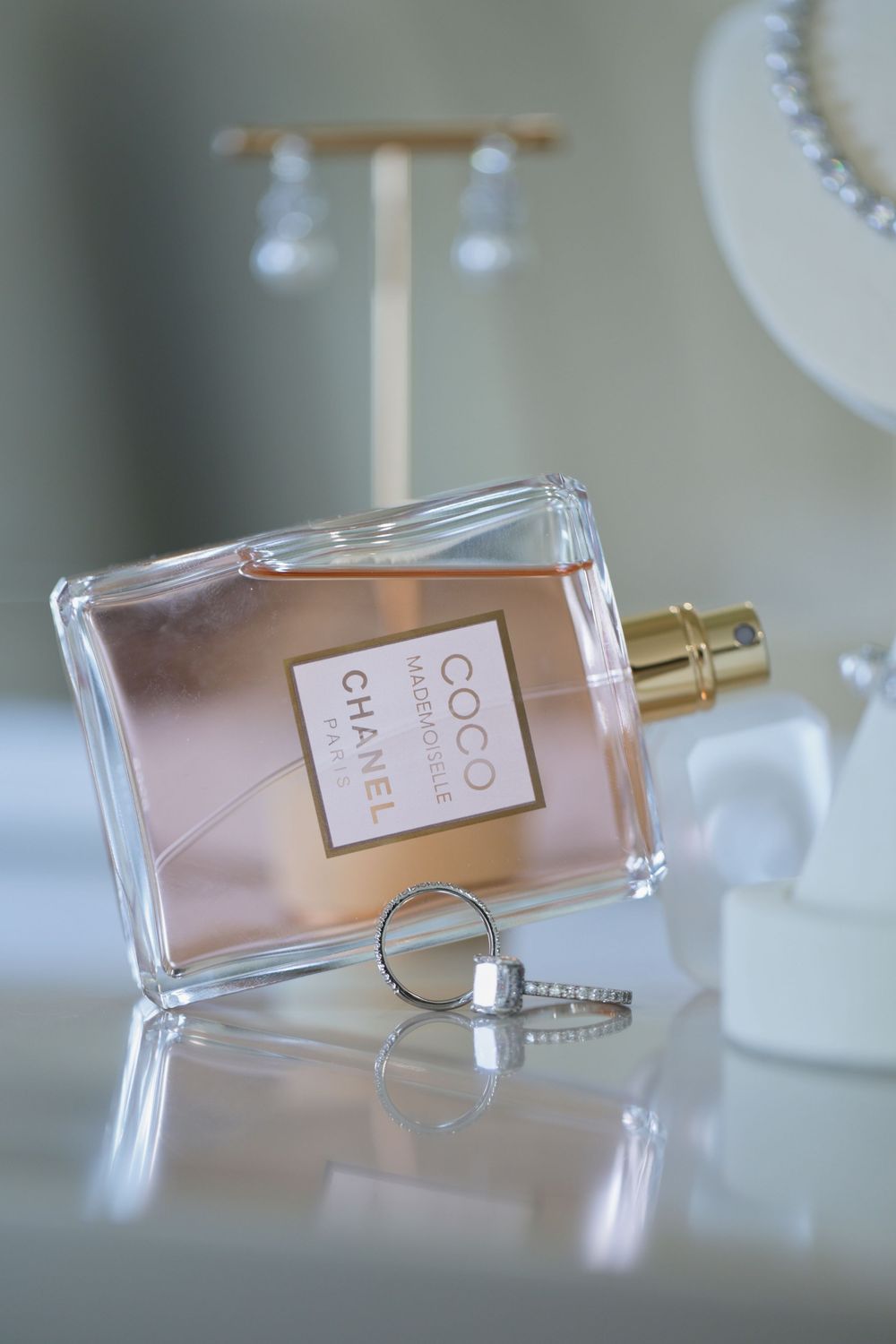 A soft and elegant perfume bottle laying sideways on a reflective surface with a blurred background.