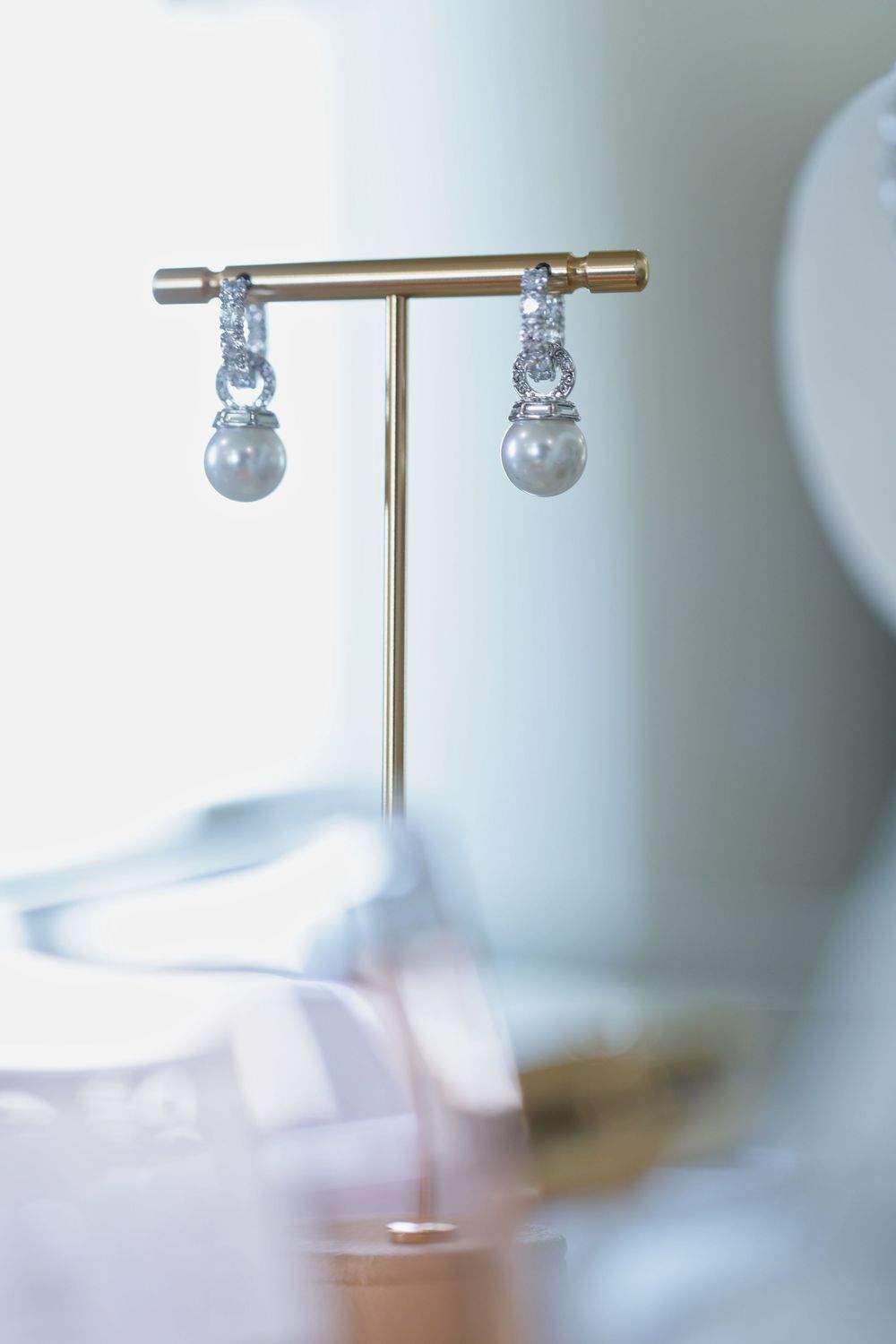 Close-up view of a minimalist silver jewelry stand with spherical pearl-like decorative elements against blurred background.
