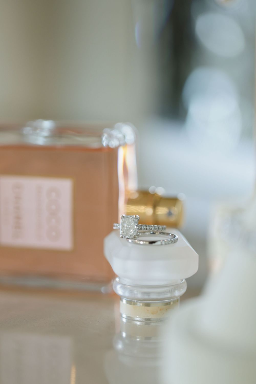 Wedding rings photographed in soft focus on a light surface with delicate lighting effects.