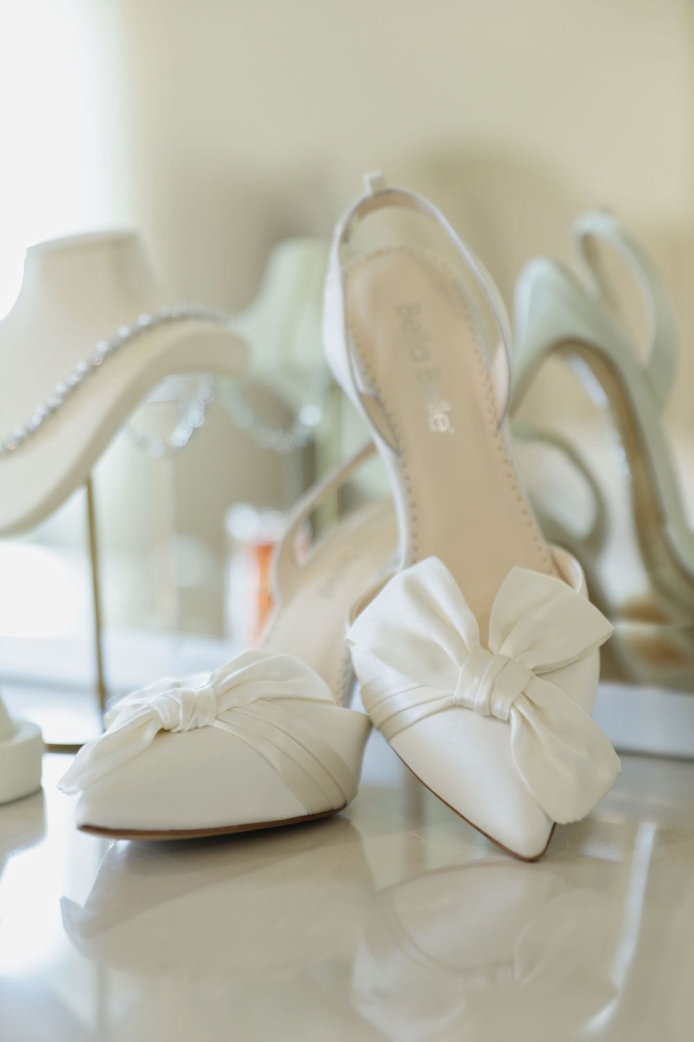 Elegant white bridal shoes with bow details arranged in a row against a light background.