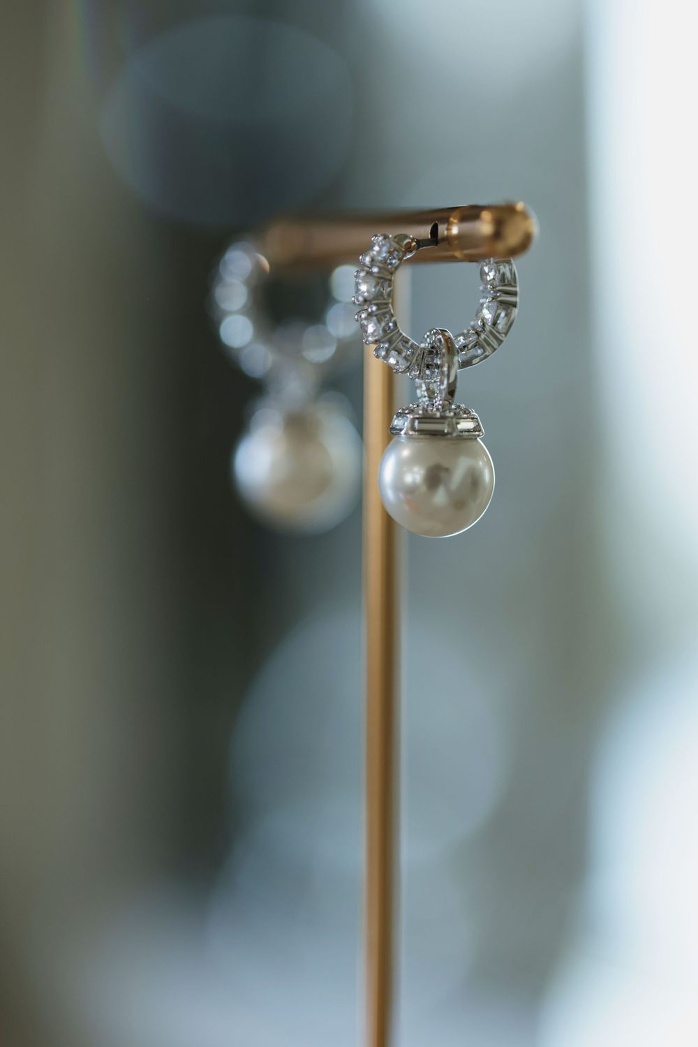 Close-up macro photograph of delicate diamond stud earrings on a gold display stand.