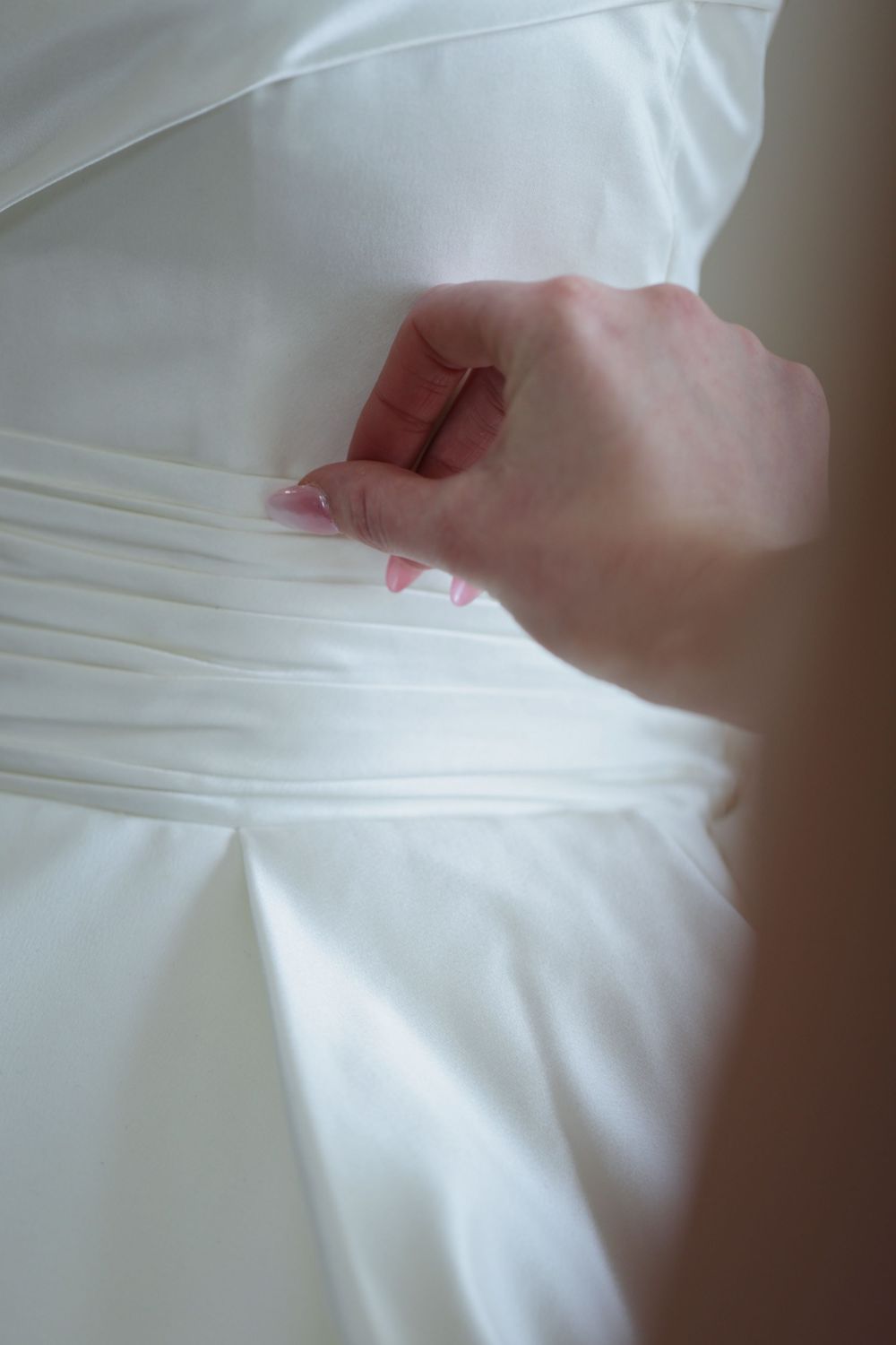 Series of hands checking the texture and smoothness of white fabric or clothing material with close up details.