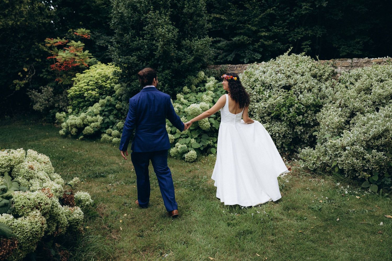 A romantic black and white wedding photograph showing a tender embrace in a natural outdoor setting.