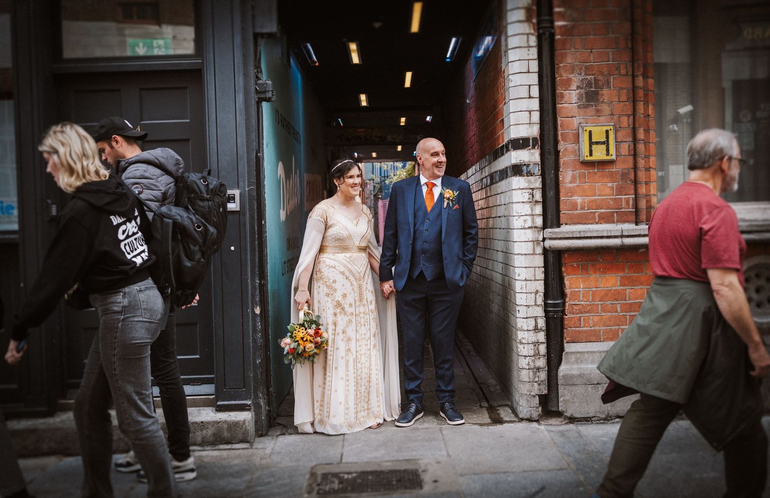 A series of wedding party photos showing people walking outside a brick building in formal attire.
