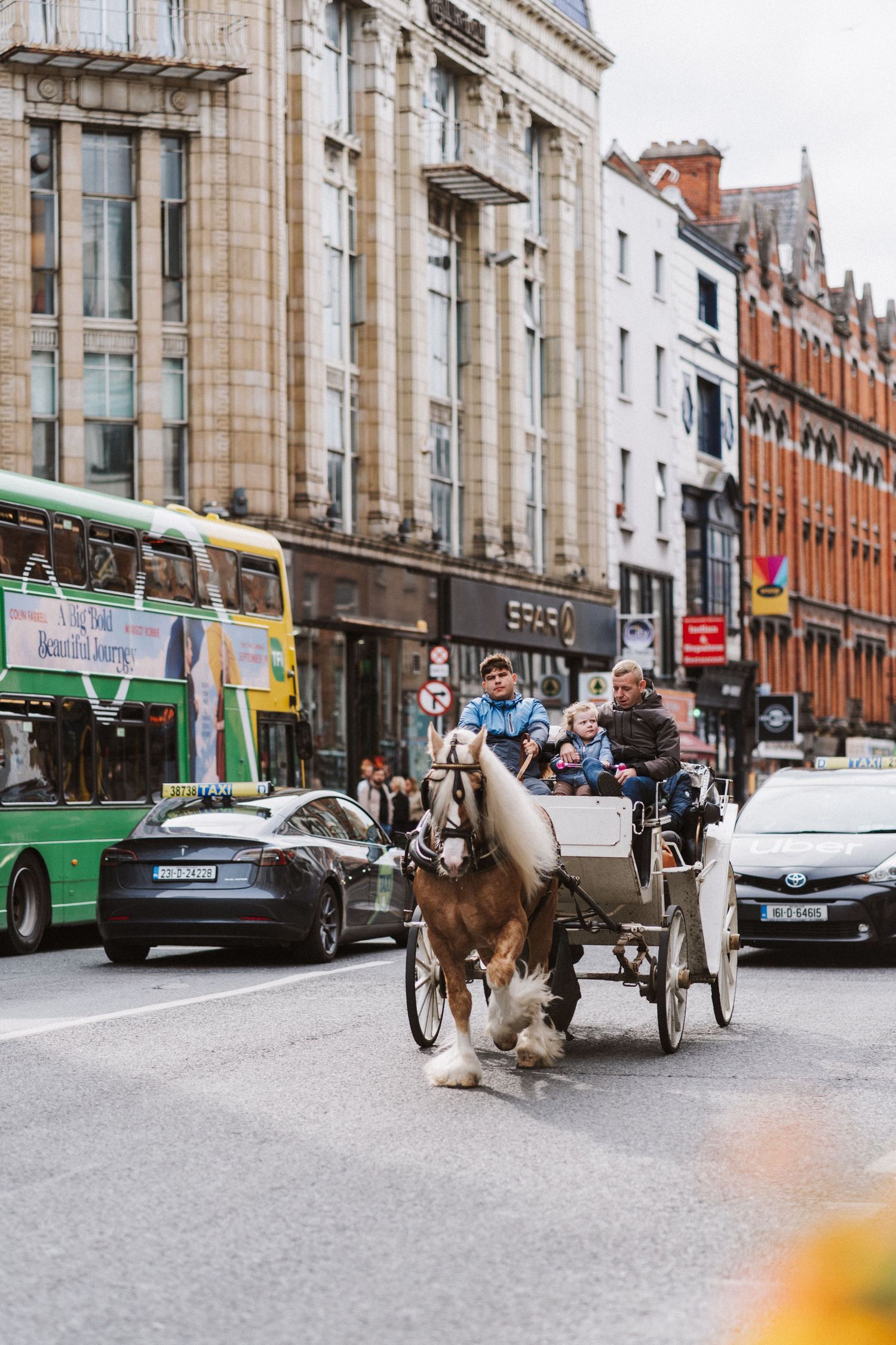 A horse-drawn carriage travels down a historic city street lined with classic architecture and modern vehicles.