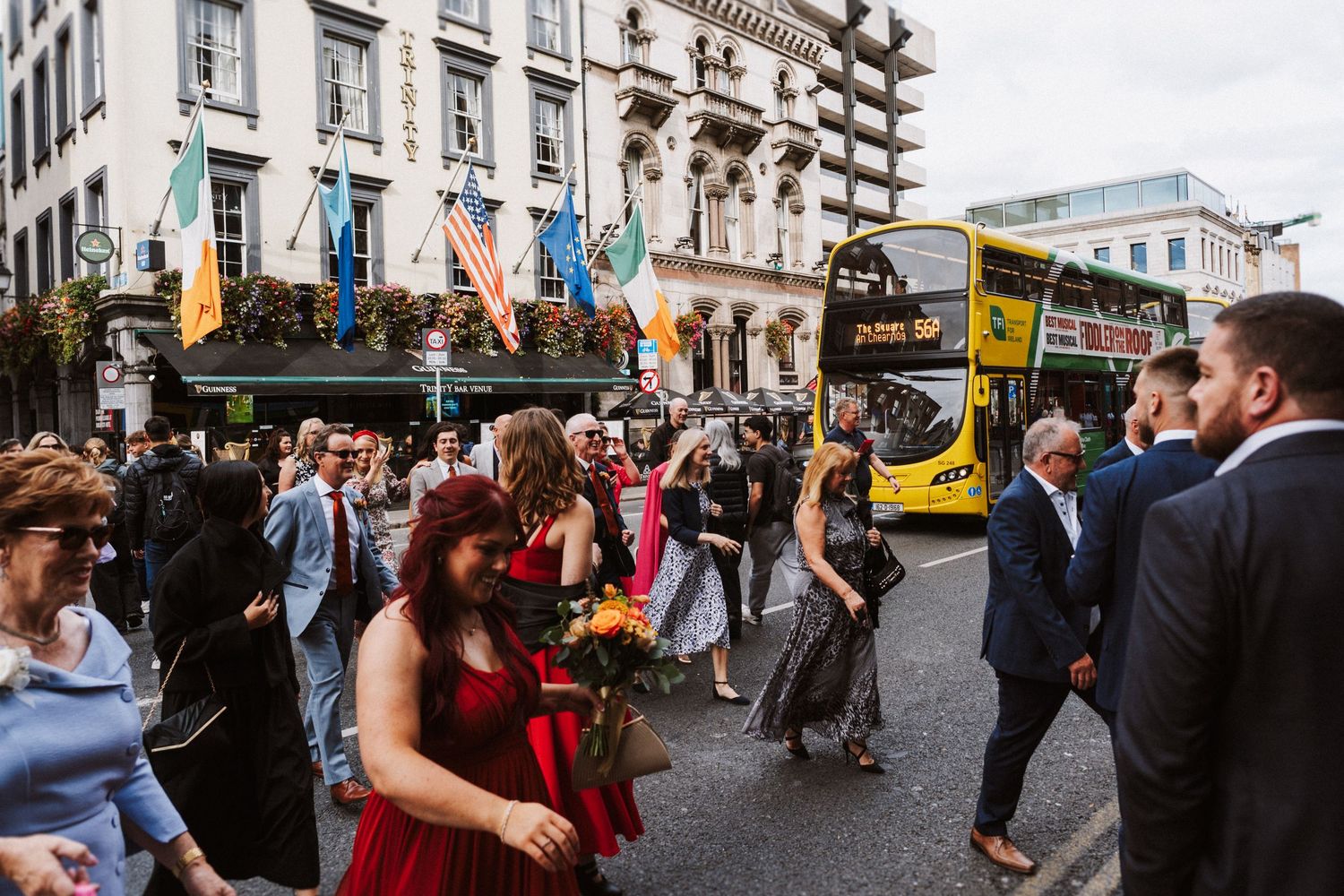 Couples dance together in a lively outdoor setting with a crowd of people in the background.