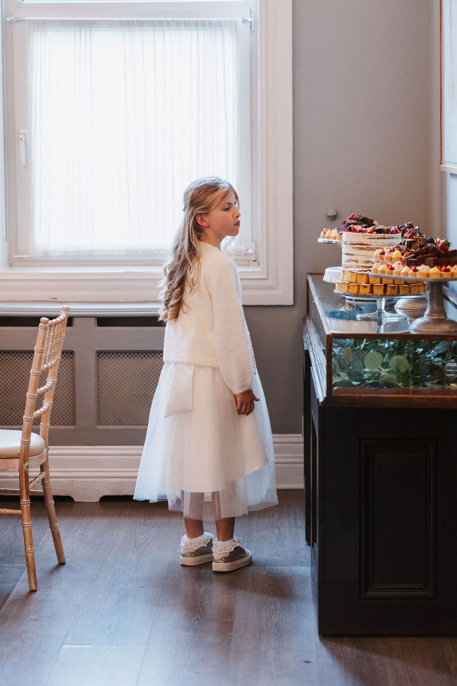 A sequence of photos showing a small child in a white dress reaching for desserts displayed on a dark table.