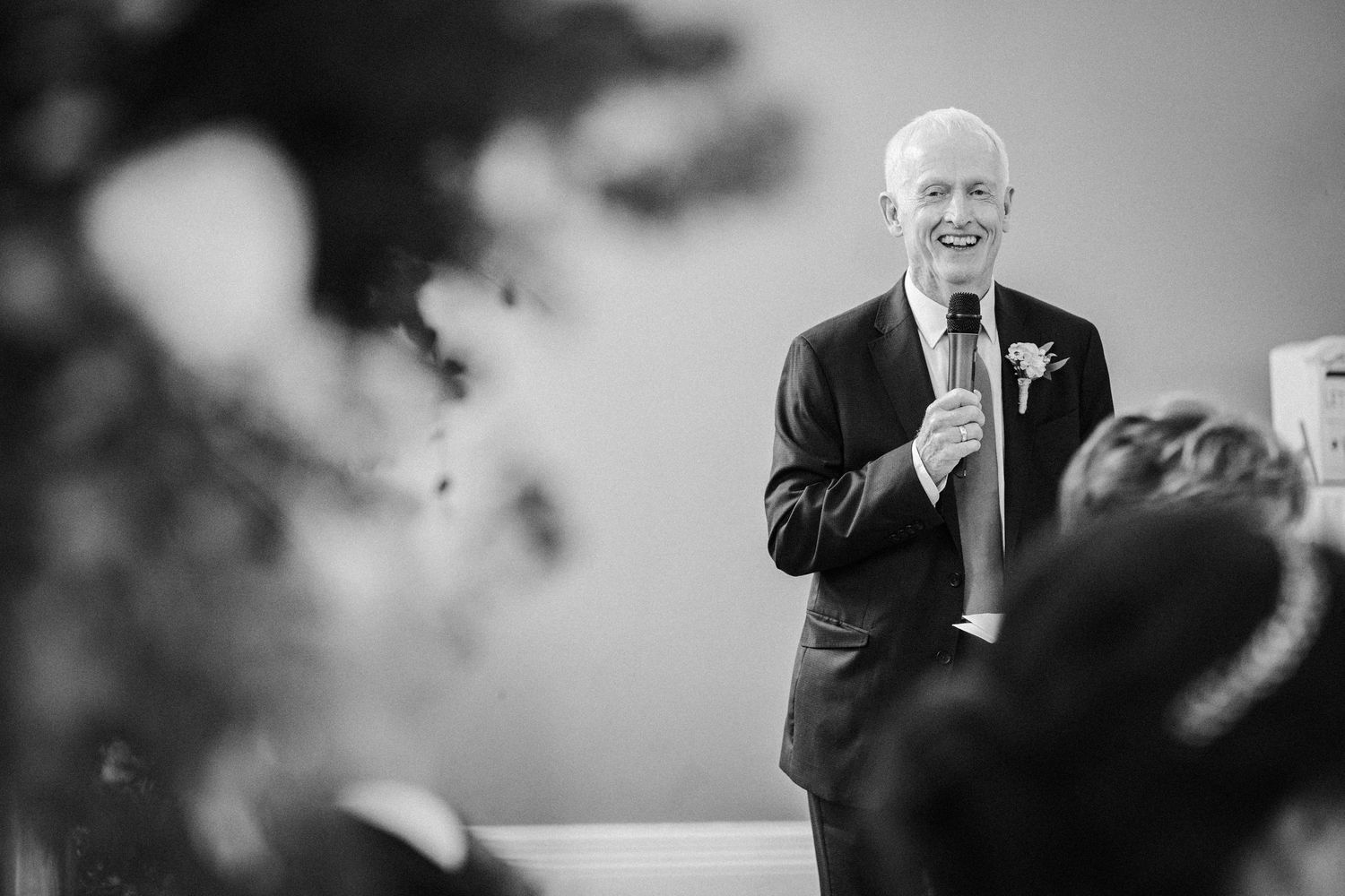 A speaker addresses an audience while holding a microphone during a formal event.