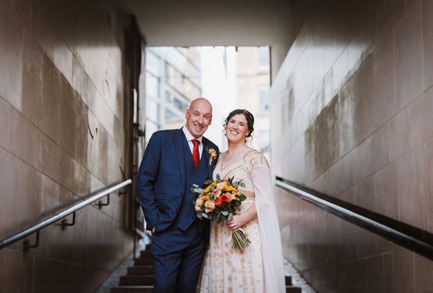 Joyful couple shares a romantic moment in a stairwell after their wedding ceremony.