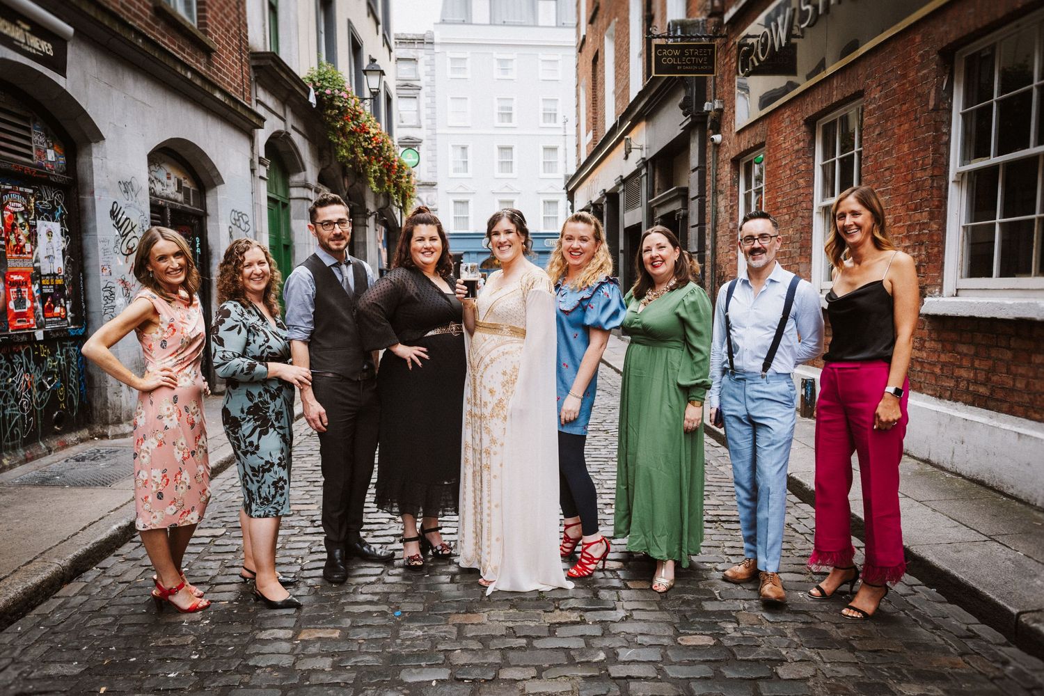 Wedding party poses together on a historic brick street in formal attire.
