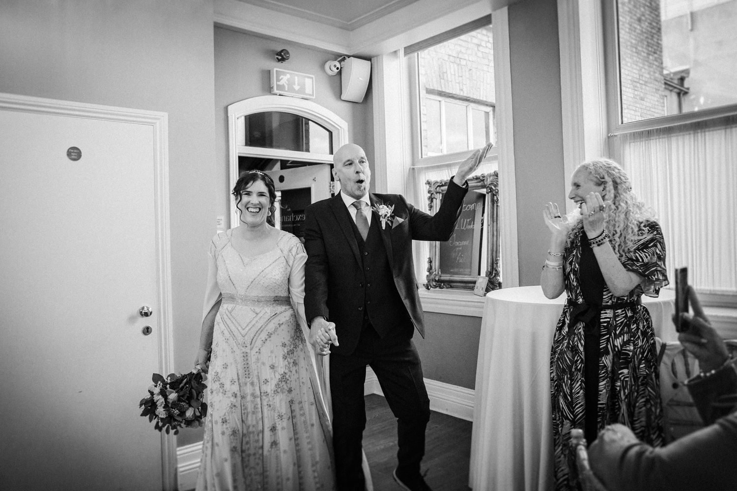 A series of black and white wedding photographs arranged in a horizontal collage showing preparation and celebratory moments.