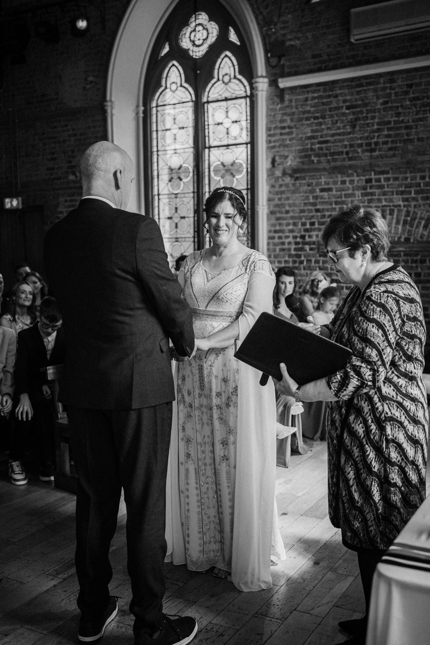 A black and white series of wedding photographs showing tender moments between figures in a church setting with arched windows.