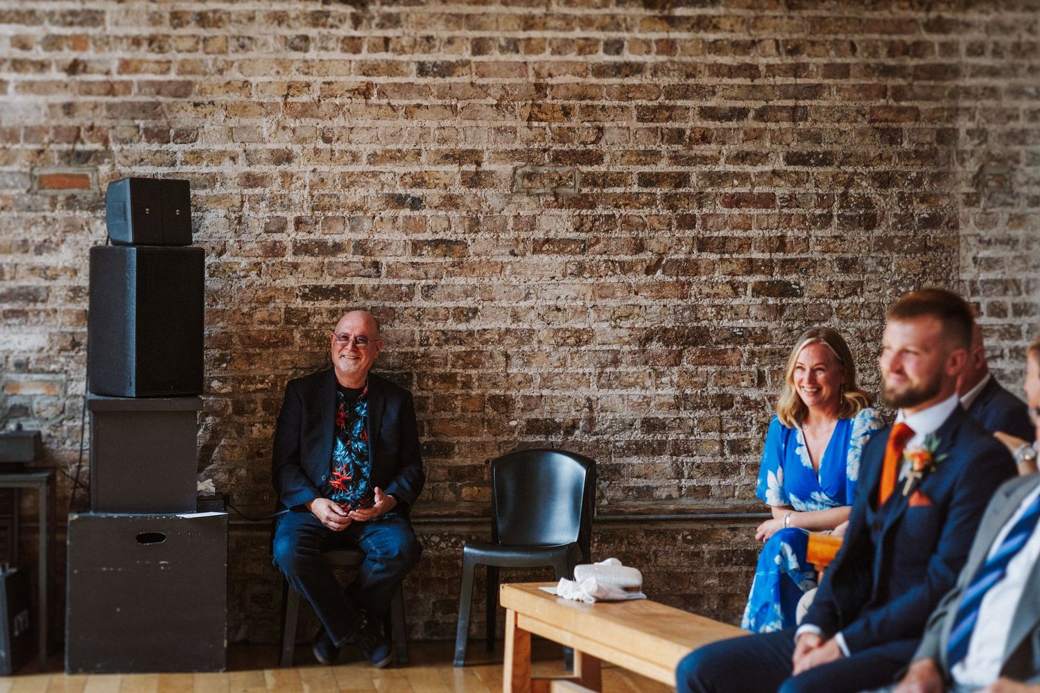 Brick wall background featuring informal business conversation in blue jackets at desk setup.