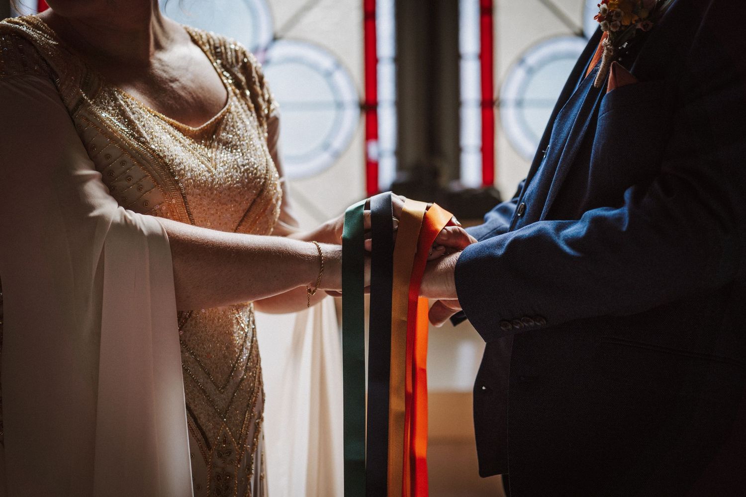 A romantic moment between two figures near a red interior column during what appears to be a wedding celebration.