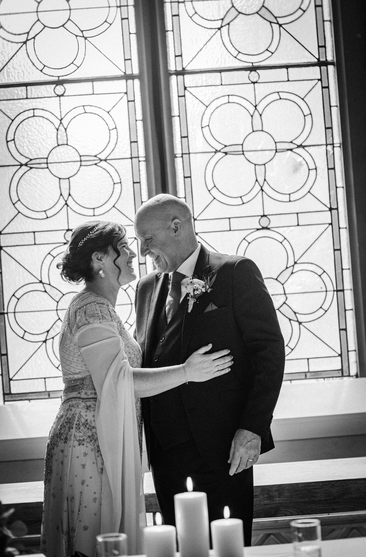A sequence of black and white romantic shots of a couple sharing intimate moments near decorative windows.