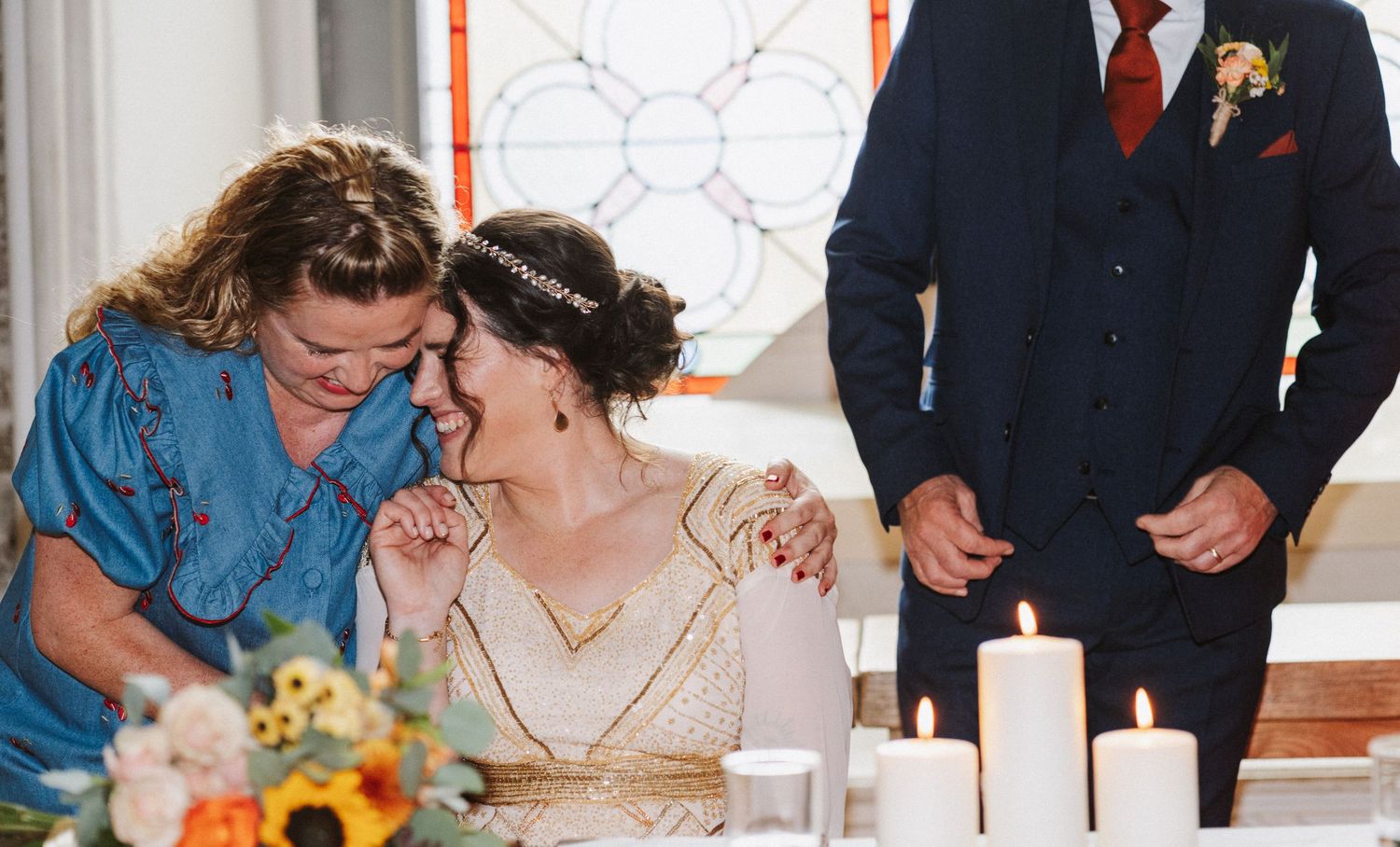 A couple signs documents during a wedding ceremony while surrounded by attendees in formal attire.