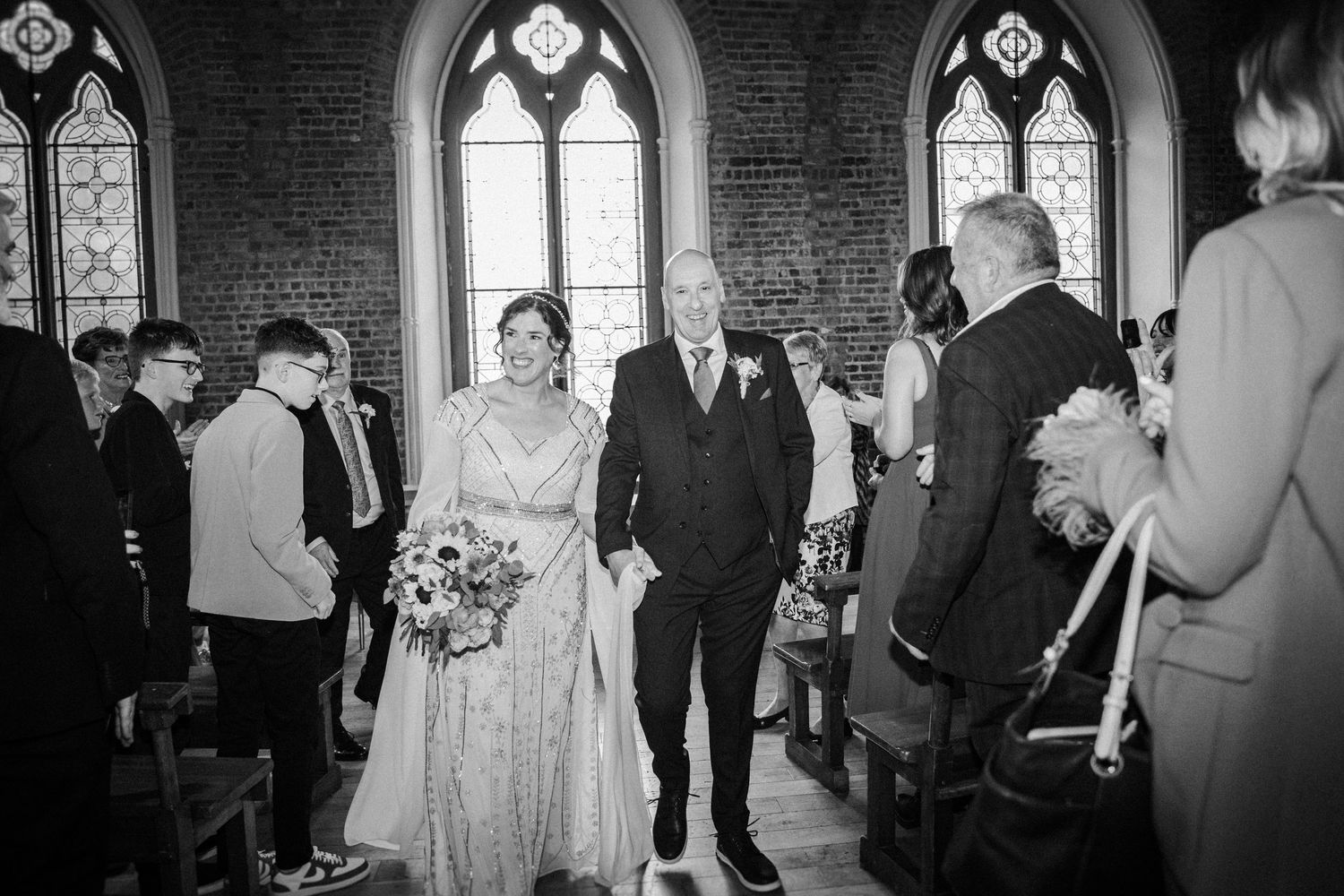 Wedding guests sing together joyfully during reception celebration in black and white photography.