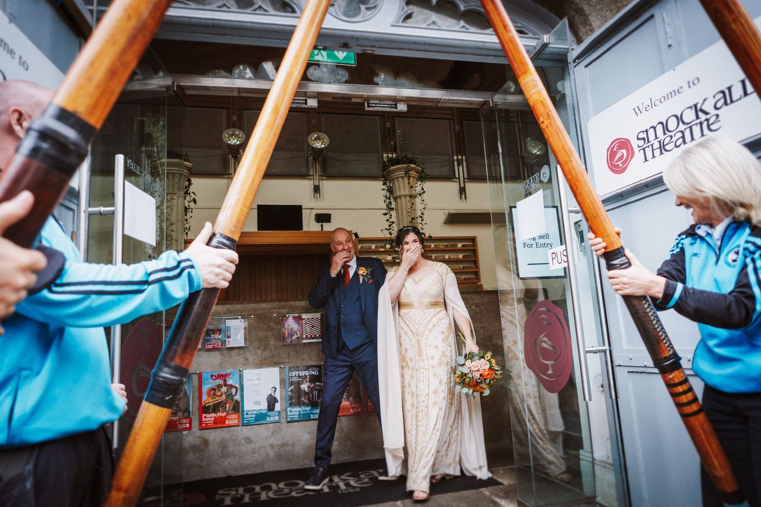 Wedding couple poses in classic reflection shot on subway train with orange poles and metallic surfaces.