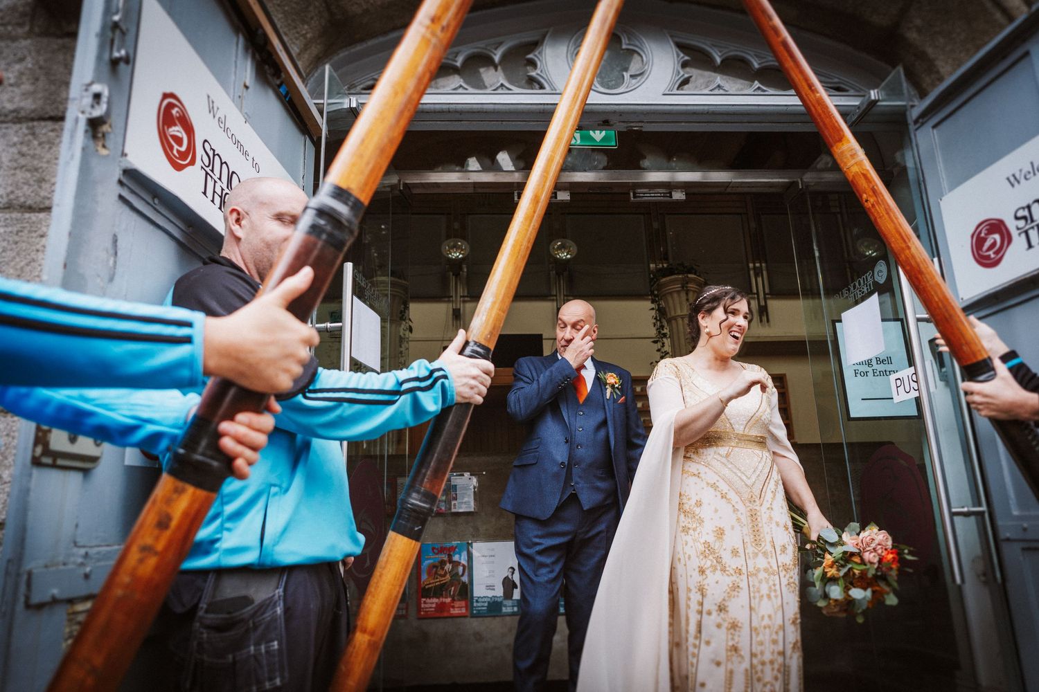 A couple poses in an urban train car during their wedding photoshoot with diagonal orange handrails visible.