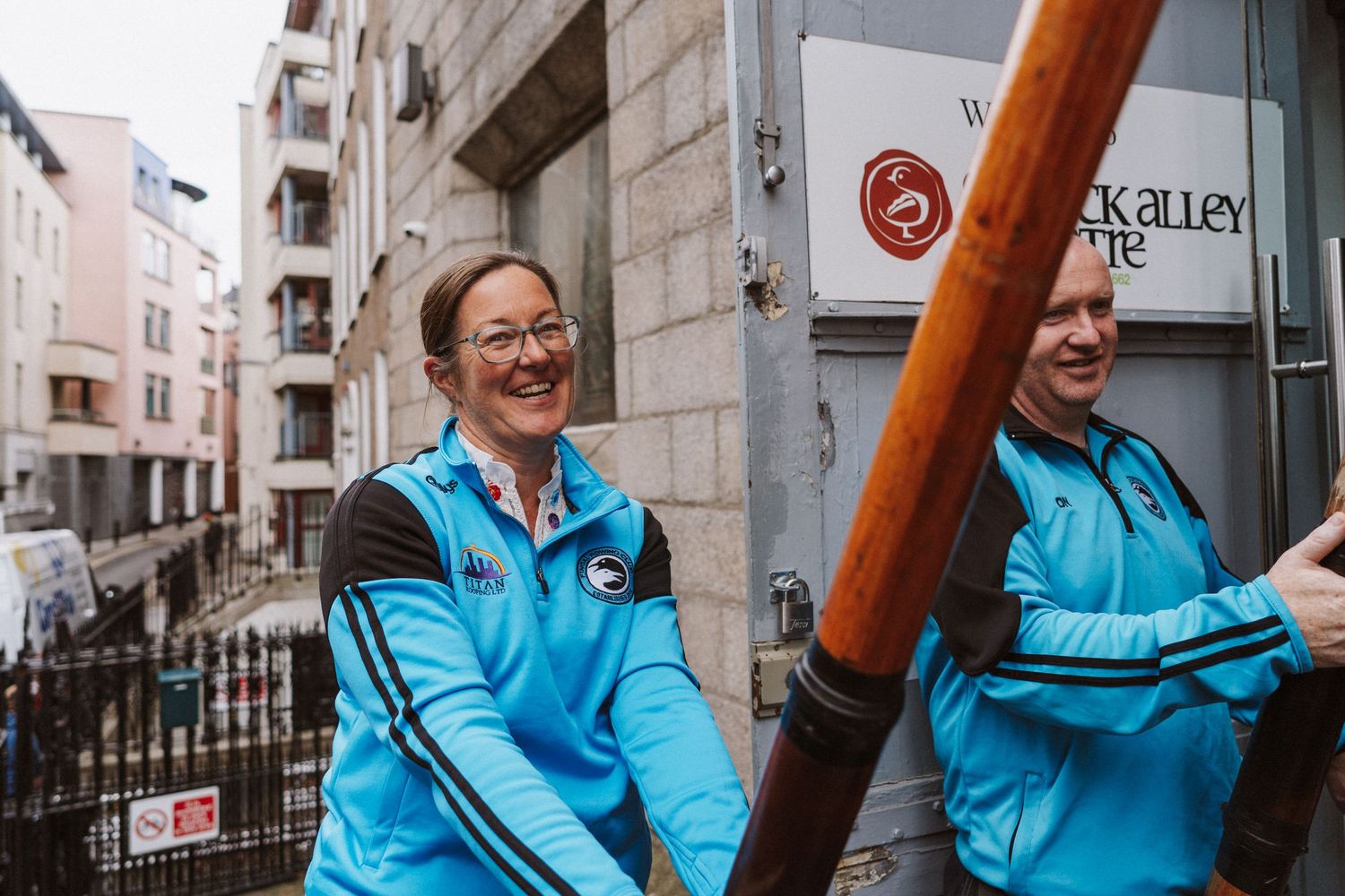 A person in a bright blue jacket holding wooden poles in different frames of a sequence shot.