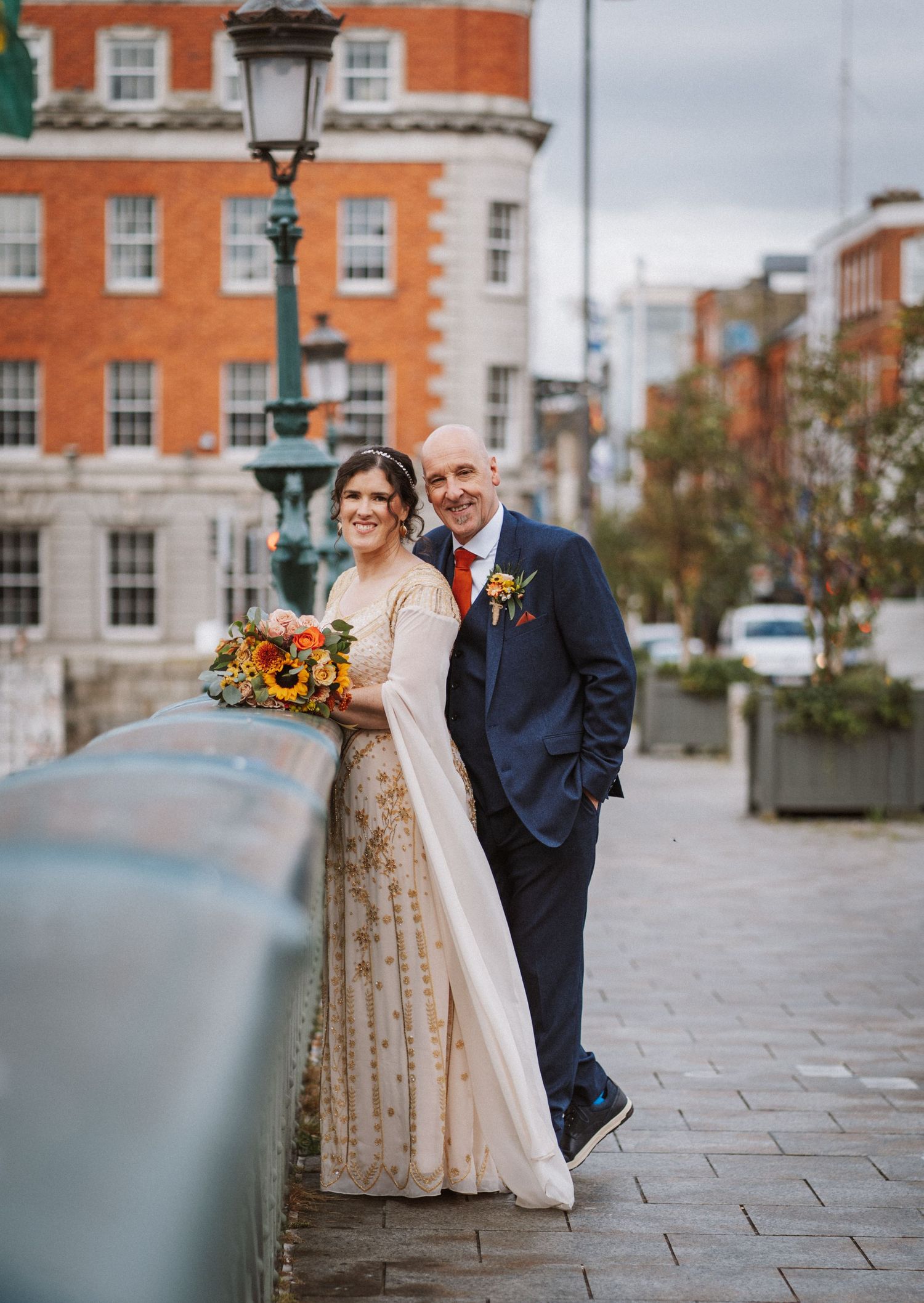 Wedding couple share a joyful moment together on a cobblestone street in front of historic brick buildings.