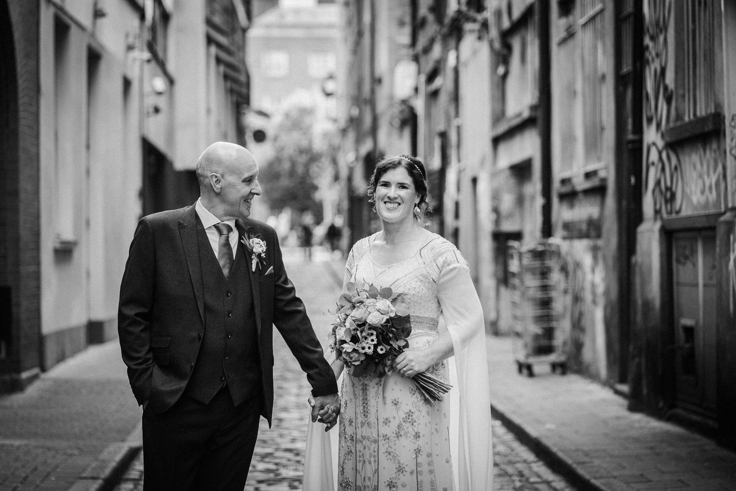 Black and white wedding photos showing couple moments together on a cobblestone street in an old city setting.