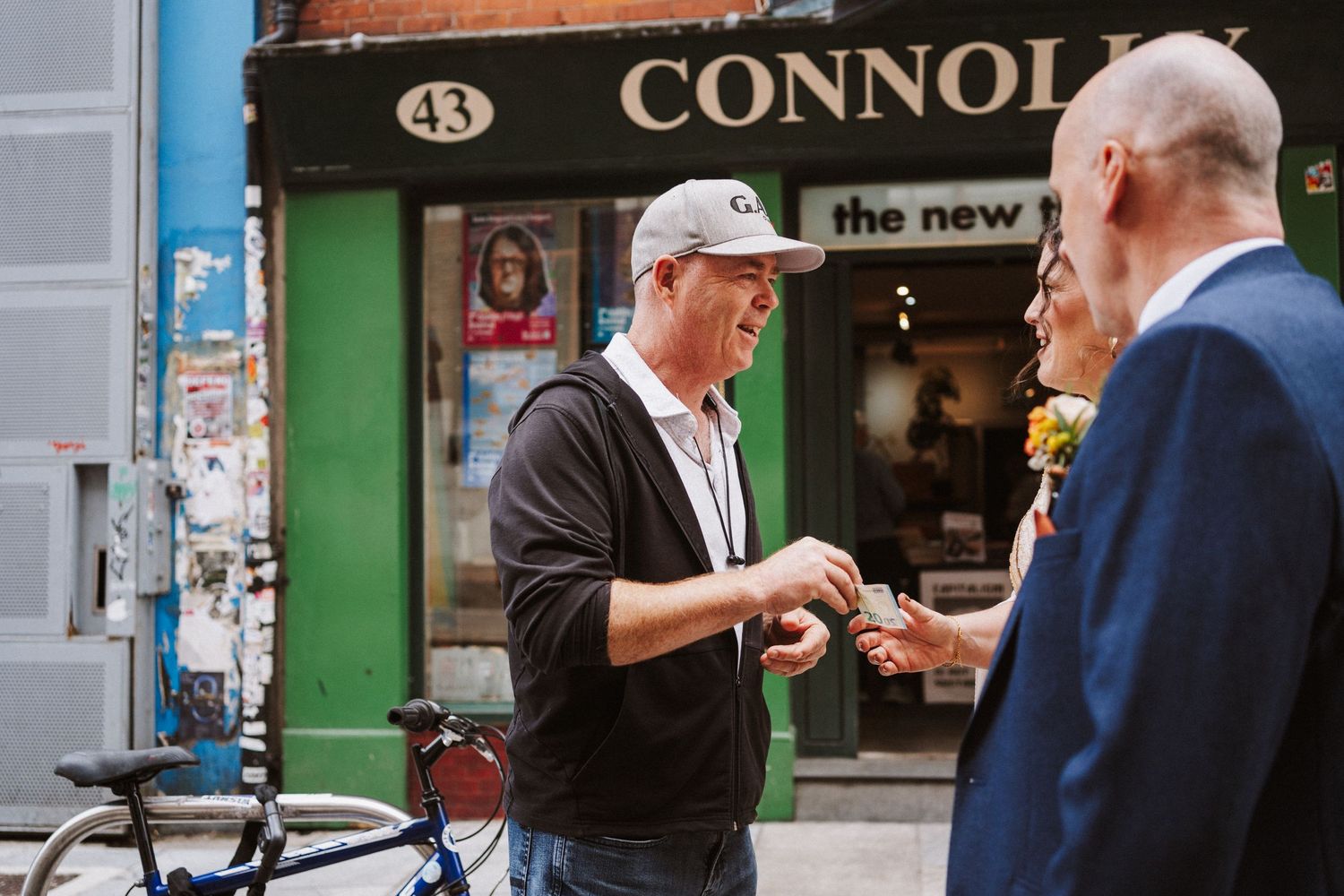 Small group of people standing and conversing together on a city sidewalk outside a storefront.
