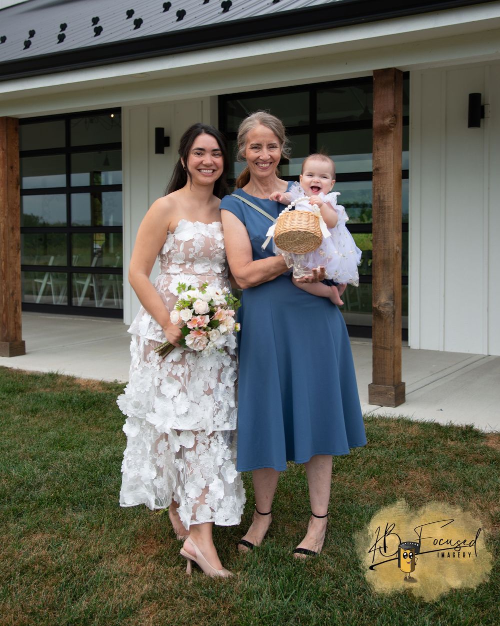 Wedding party members gather for photos outside a white building with wooden beams.